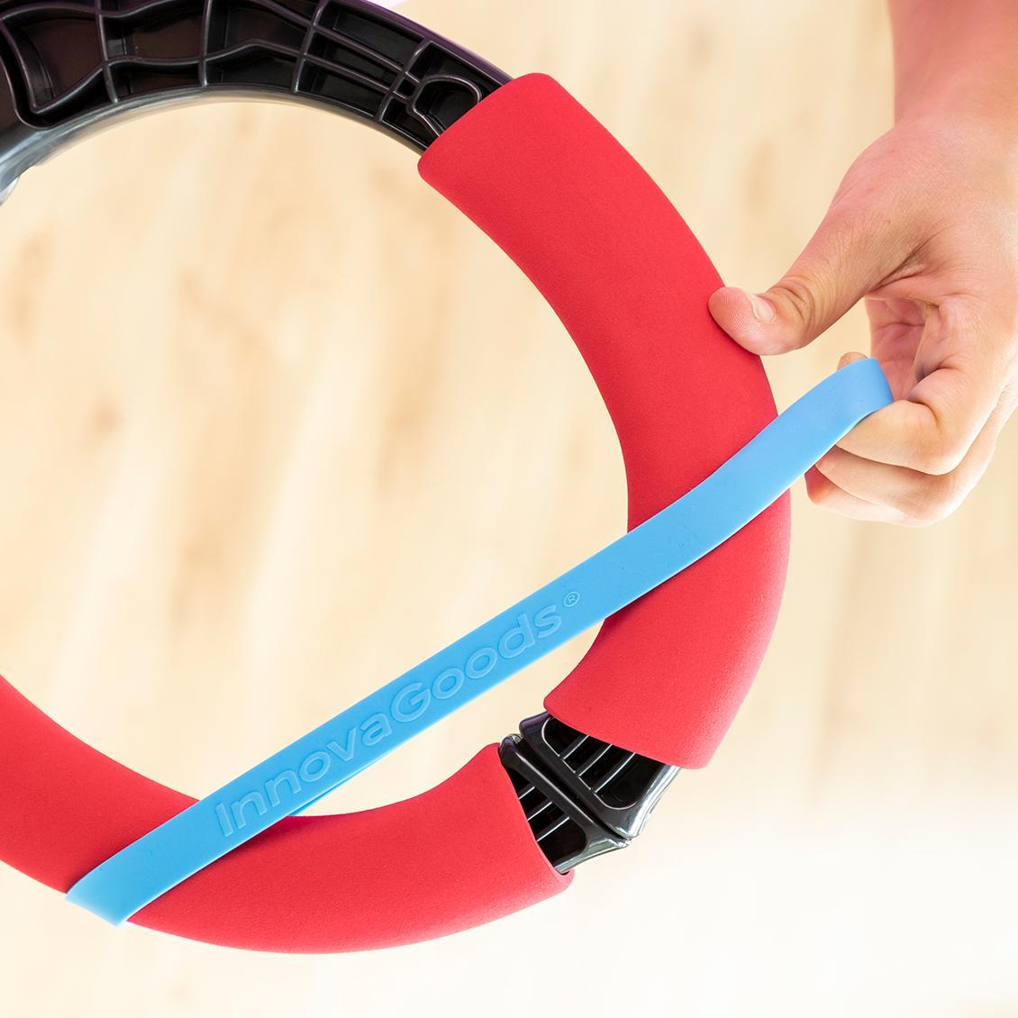 Nahaufnahme einer Hand, die einen Fitnessring mit blauem Band hält. Rote gepolsterte Abschnitte am Ring.