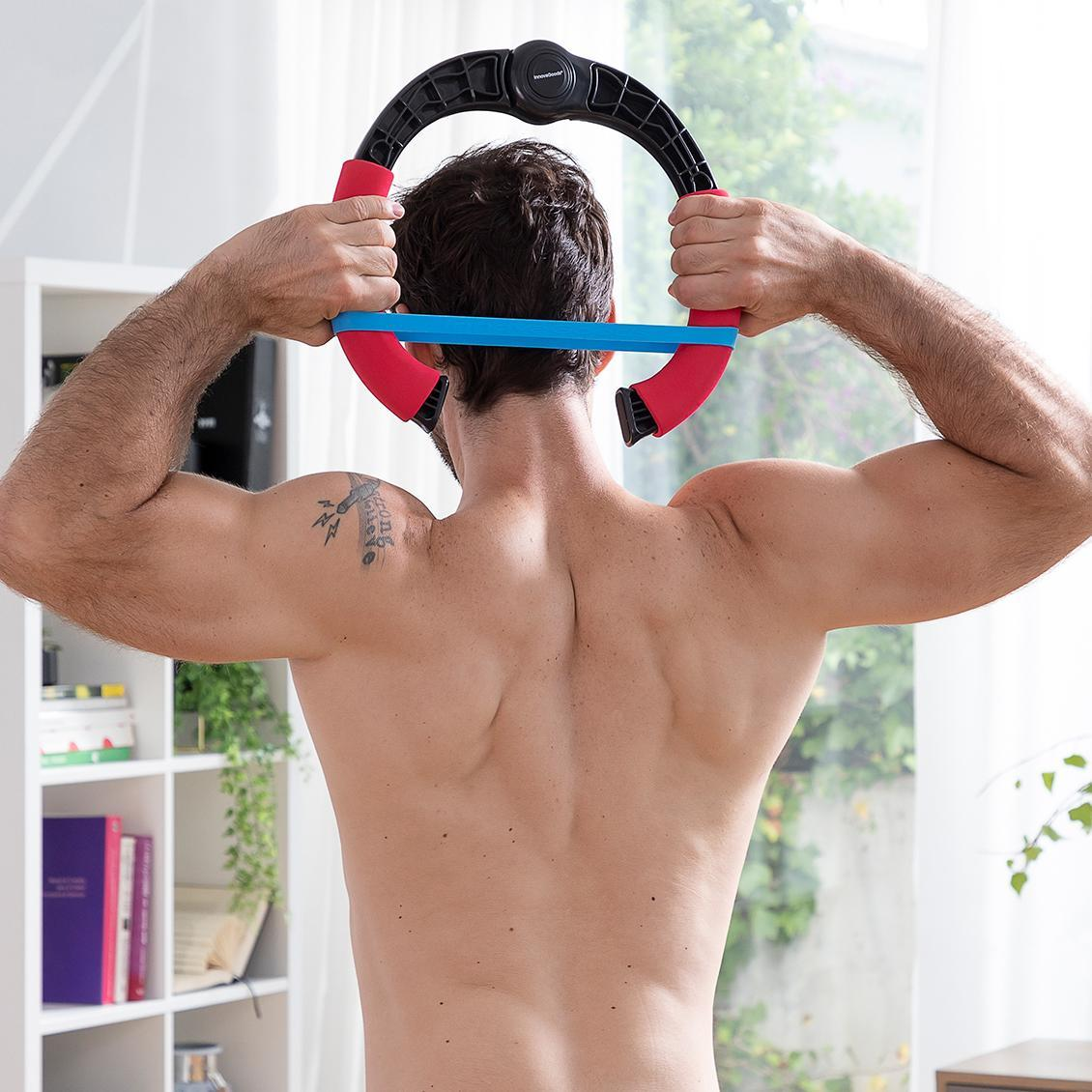 Mann von hinten, hält einen Fitnessring hinter dem Nacken. Ein Tattoo ist auf seinem Rücken.