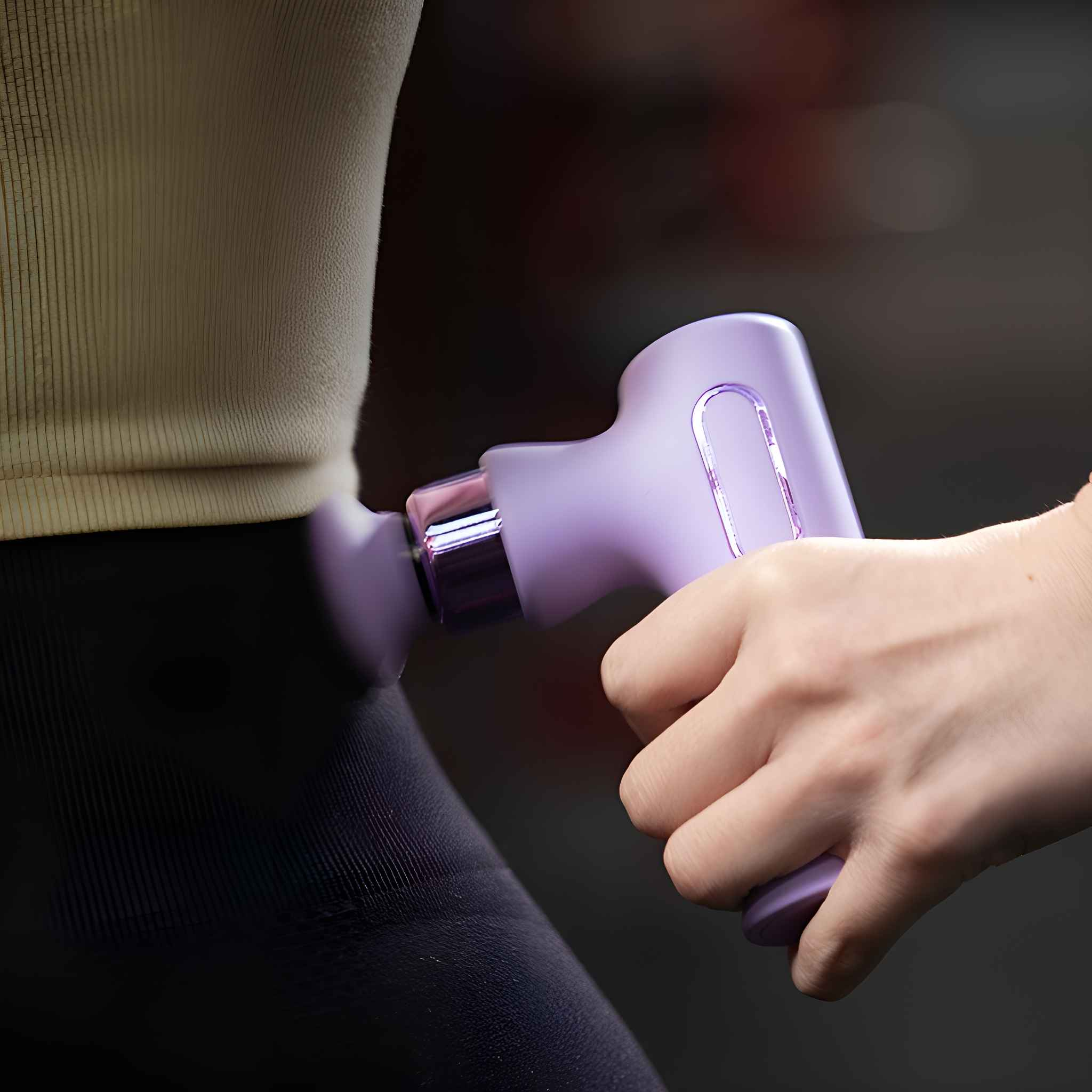 Eine Person benutzt eine violette Massagepistole an ihrer Hüfte. Die Haut ist sichtbar.