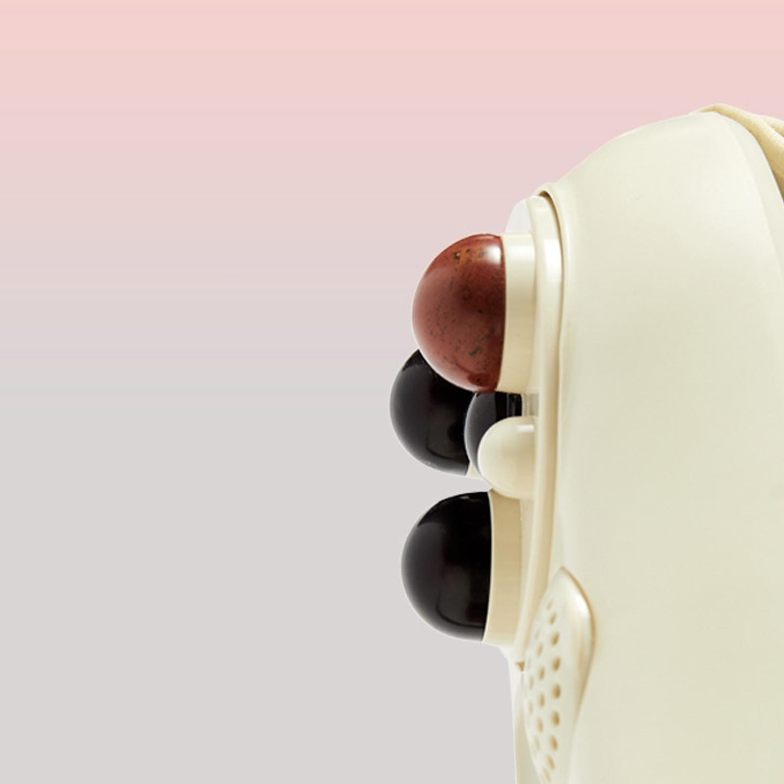Nahaufnahme eines Massagegeräts mit Massageköpfen. Neutraler Hintergrund. Gerät ist cremefarben.