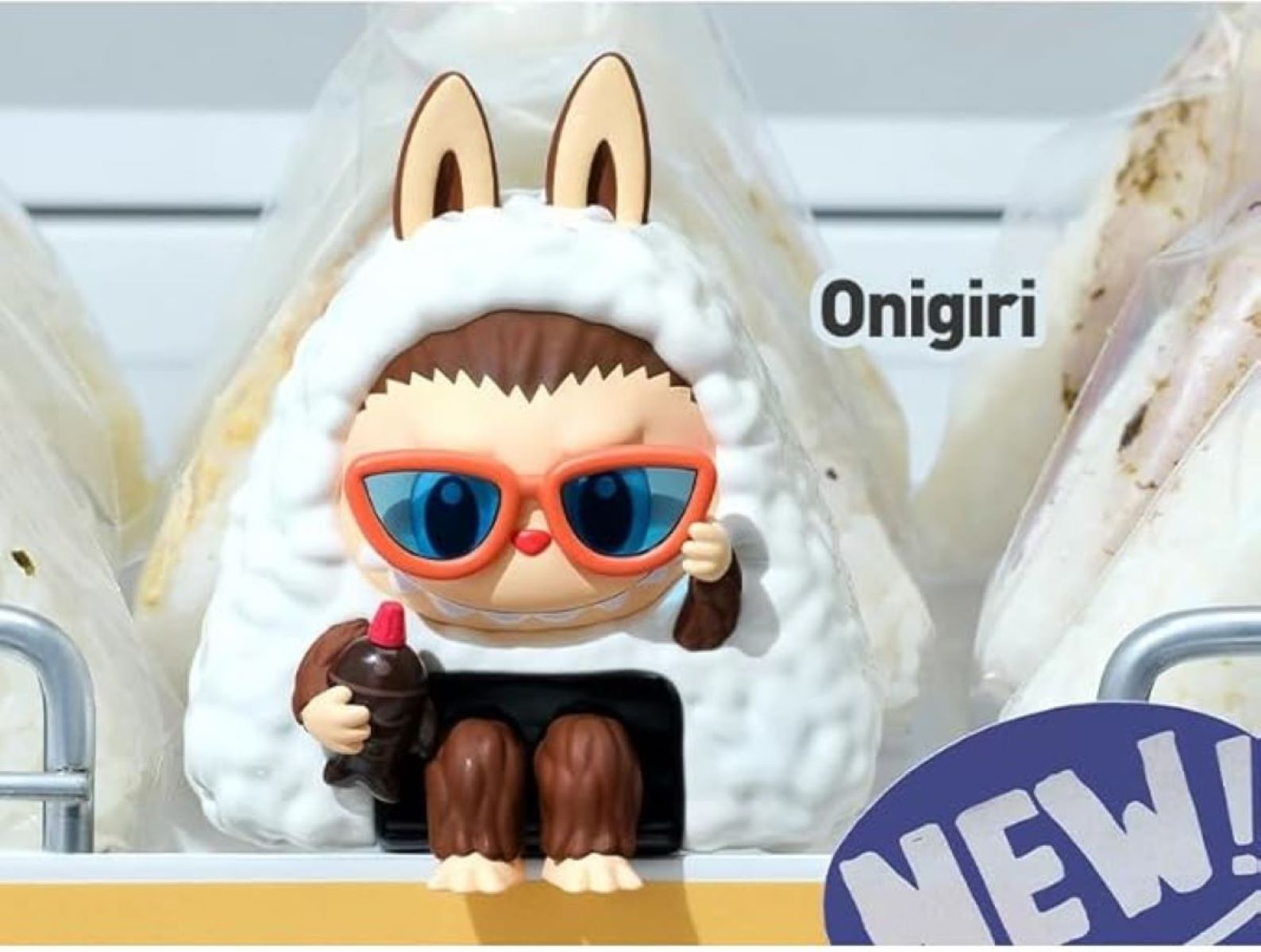 Un personaggio giocattolo con un abito bianco soffice che tiene una piccola bottiglia e indossa occhiali da sole.