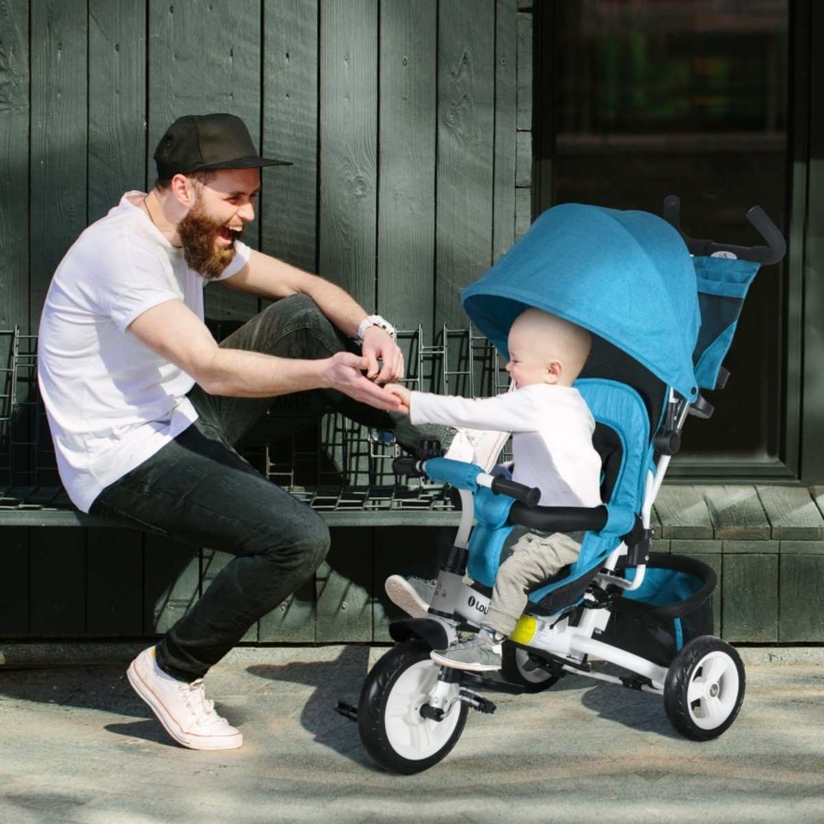 Ein Vater und ein Baby in einem Dreirad, der Vater lacht und das Baby greift nach seiner Hand.