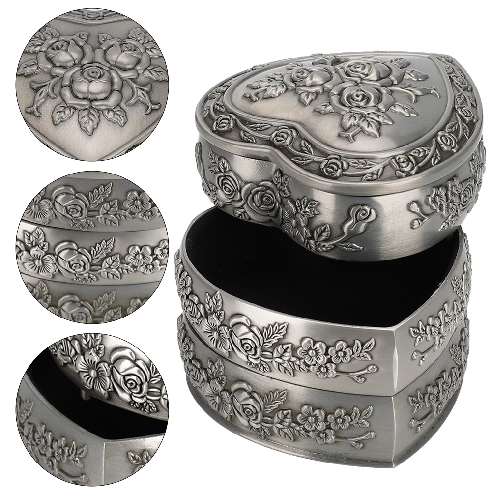 Silberne herzförmige Schmuckschatulle, Deckel offen. Blumendesign auf Deckel und Schichten. Schwarzer Innenraum.