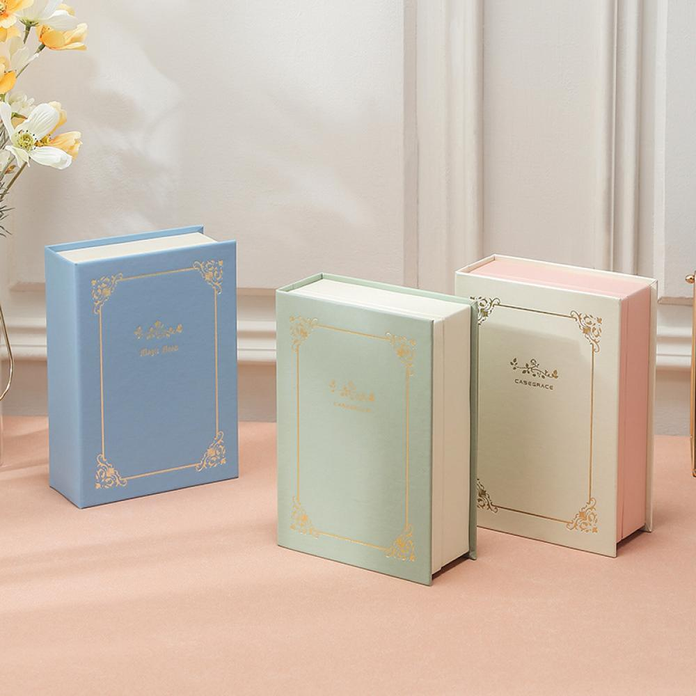Drei buchförmige Schachteln in Blau, Grün und Rosa mit goldenen dekorativen Rändern.
