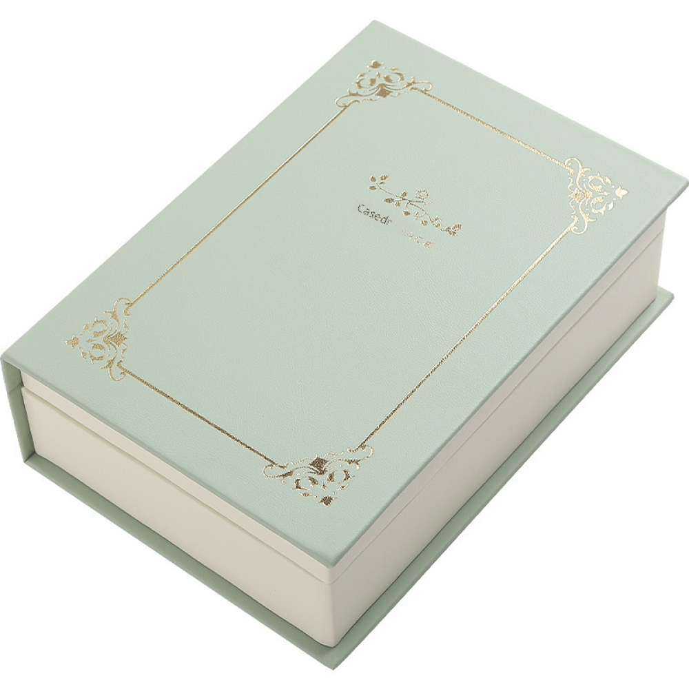 Eine geschlossene, mintgrüne, buchförmige Schachtel mit goldenen dekorativen Rändern und Text auf dem Deckel.