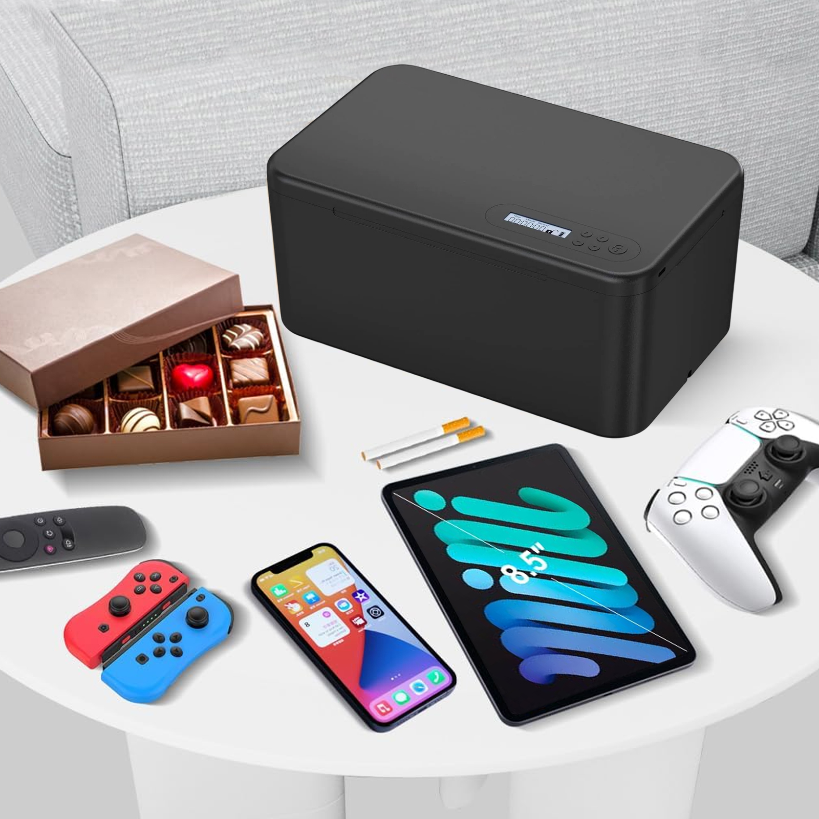 Tisch mit verschiedenen Gegenständen: Pralinen, Telefon, Tablet, Gamecontroller, Zigaretten und eine schwarze Box.