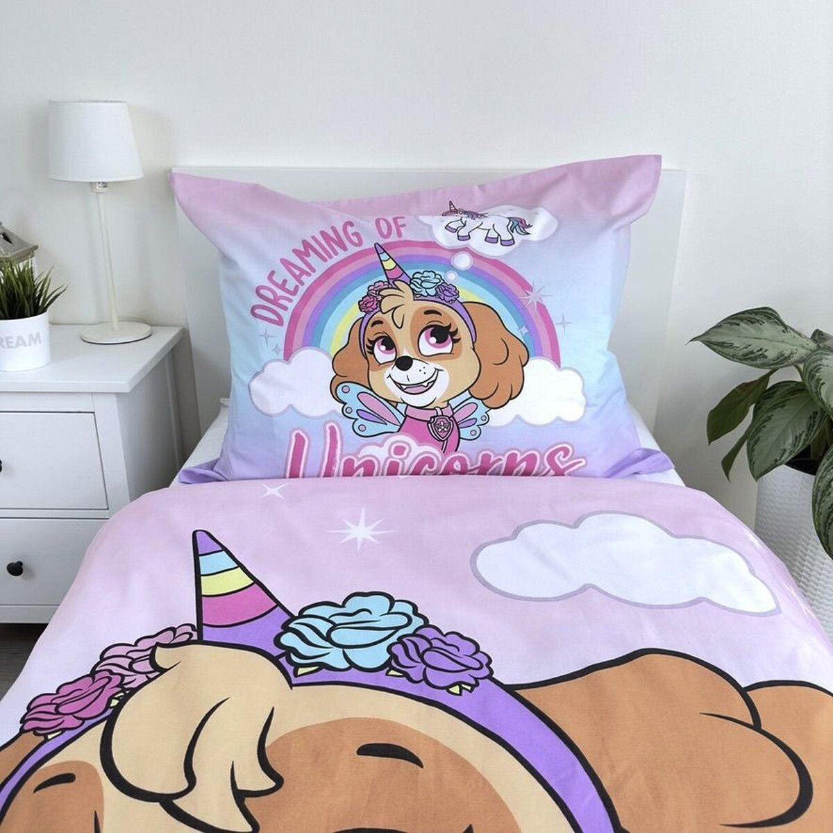 Bettwäsche-Set mit Skye von Paw Patrol als Einhorn. Mit einem weißen Nachttisch und einer grünen Pflanze.
