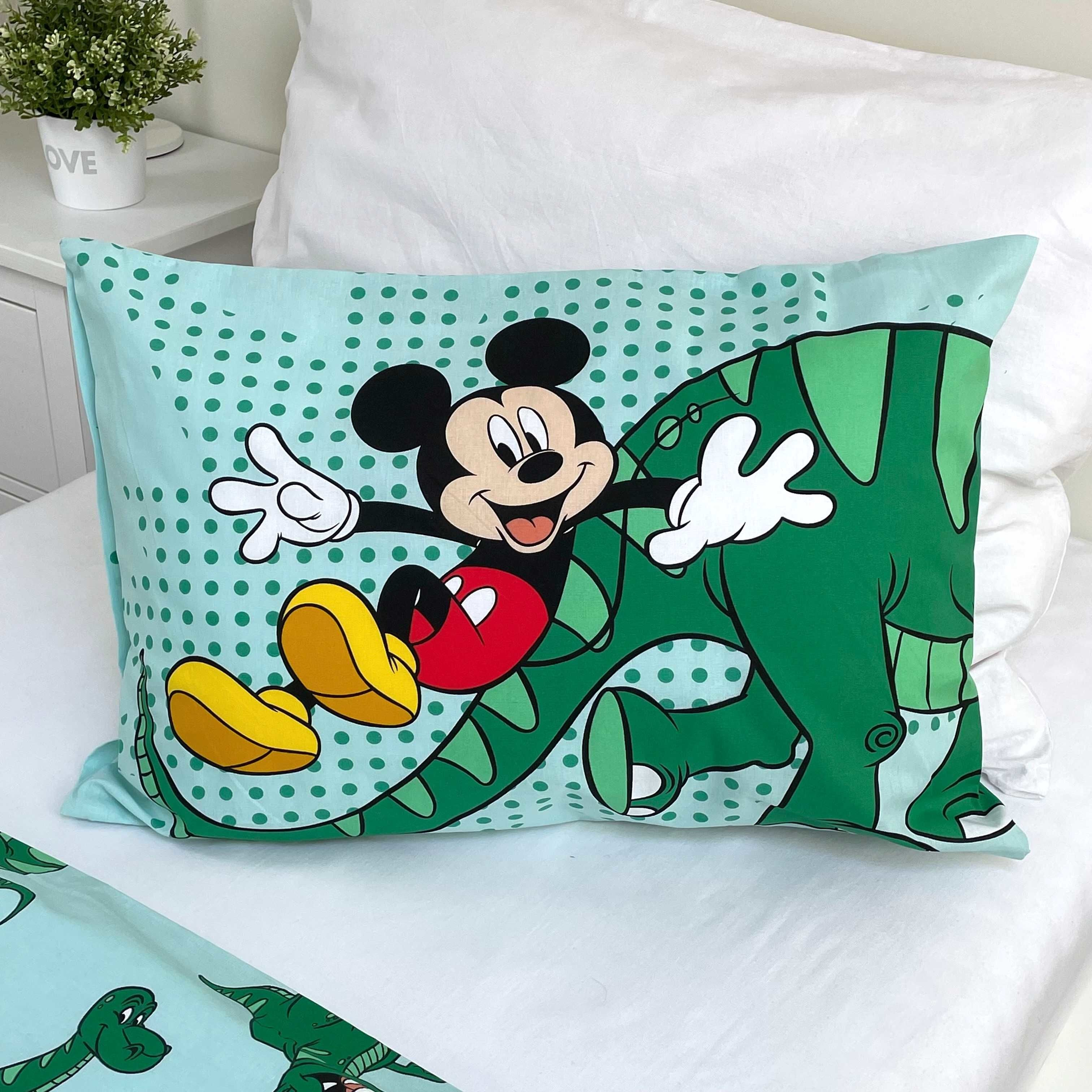 Kissenbezug mit Mickey Mouse, die einen grünen Dinosaurier reitet. Weißes Bett und Hintergrund.