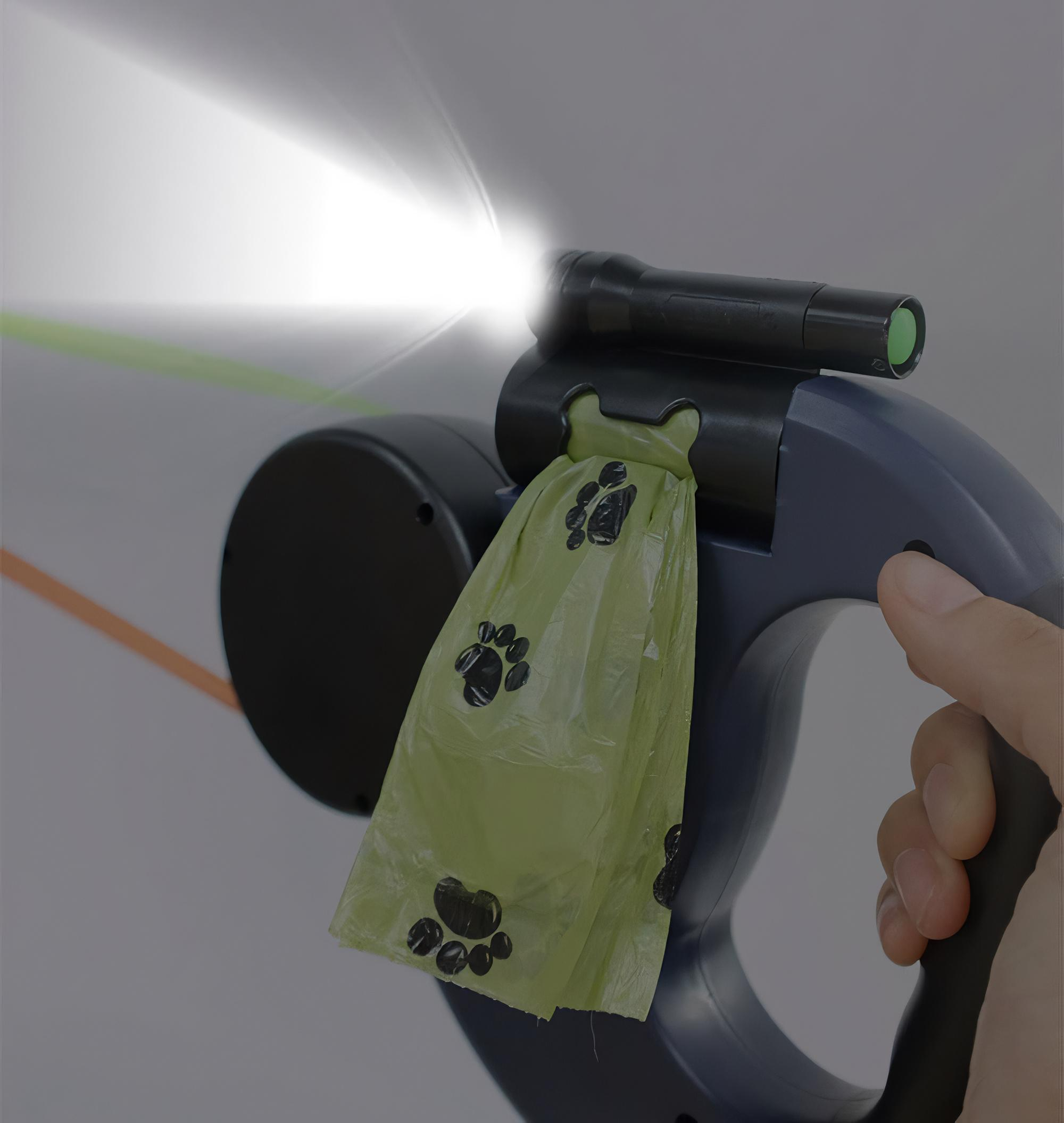 Eine Hand, die eine Hundeleine mit einer Taschenlampe und einem Beutelspender mit einem grünen Beutel und einem weißen Hintergrund hält.