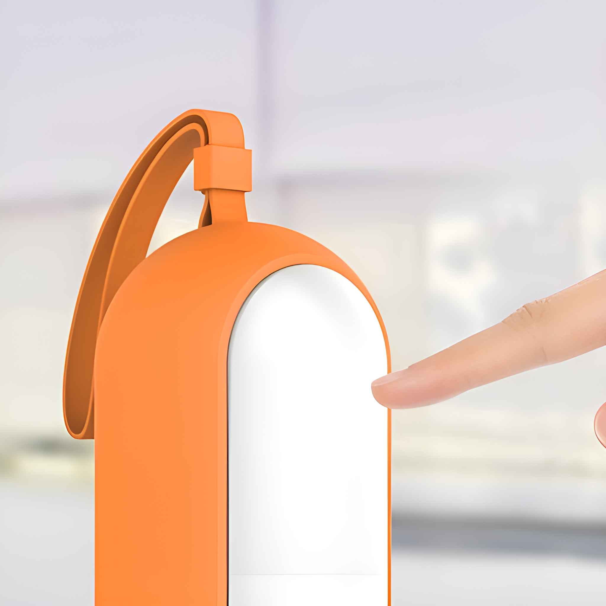 Ein Finger berührt die weiße Oberfläche eines orangefarbenen Geräts mit einer Handschlaufe.