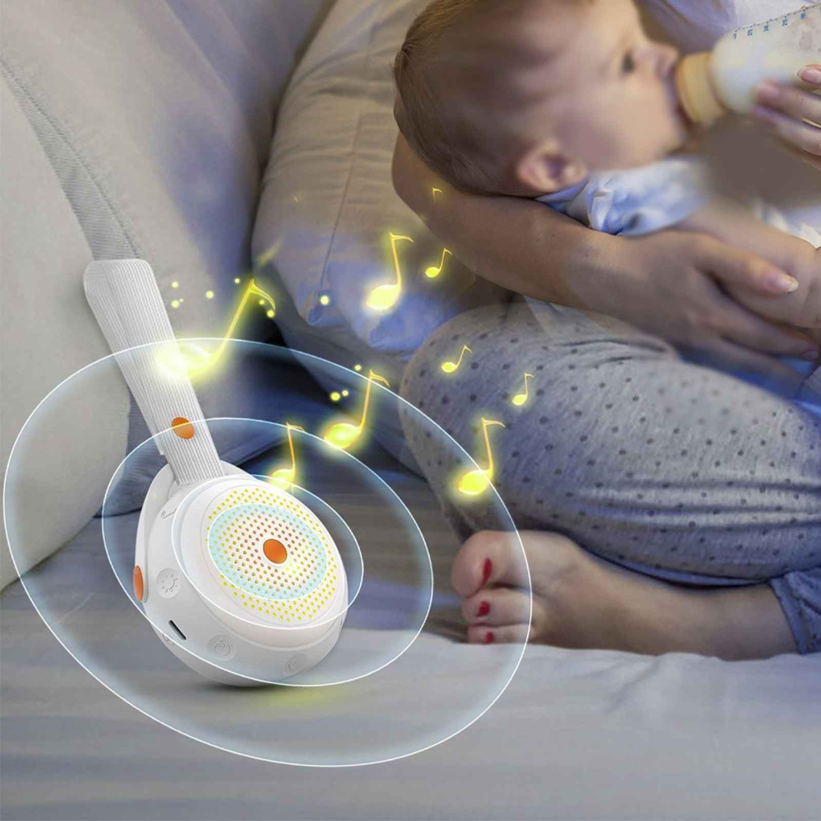 Ein Baby wird mit einer Flasche gefüttert, während eine Klangmaschine spielt, mit Noten die strahlen.