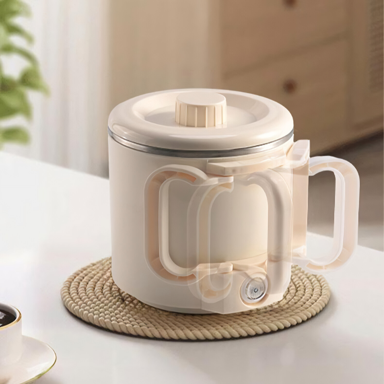 Ein cremefarbener elektrischer Wasserkocher auf einer gewebten Matte auf einem weissen Tisch.