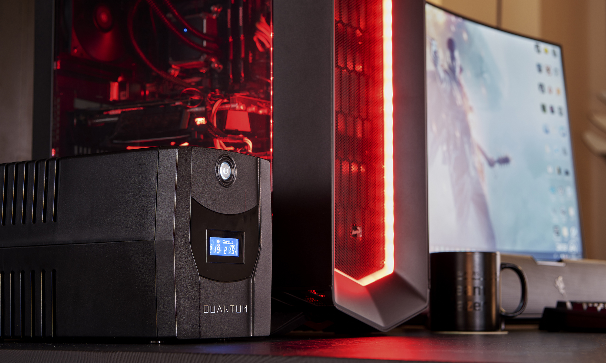 Una scrivania con un UPS, un case del computer, un monitor e una tazza.