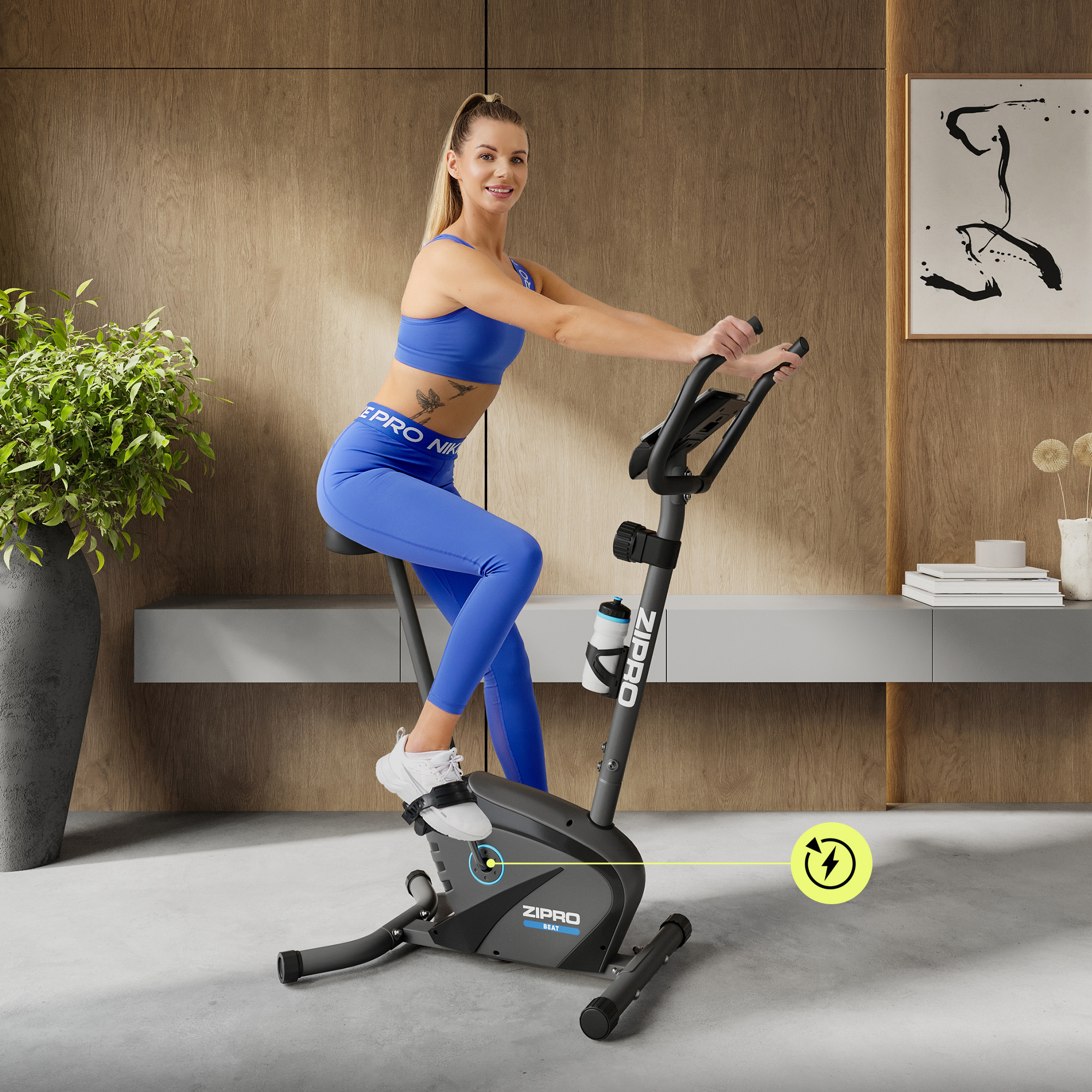Frau in Blau trainiert auf einem schwarzen Heimtrainer in einem Raum mit Holzverkleidung.