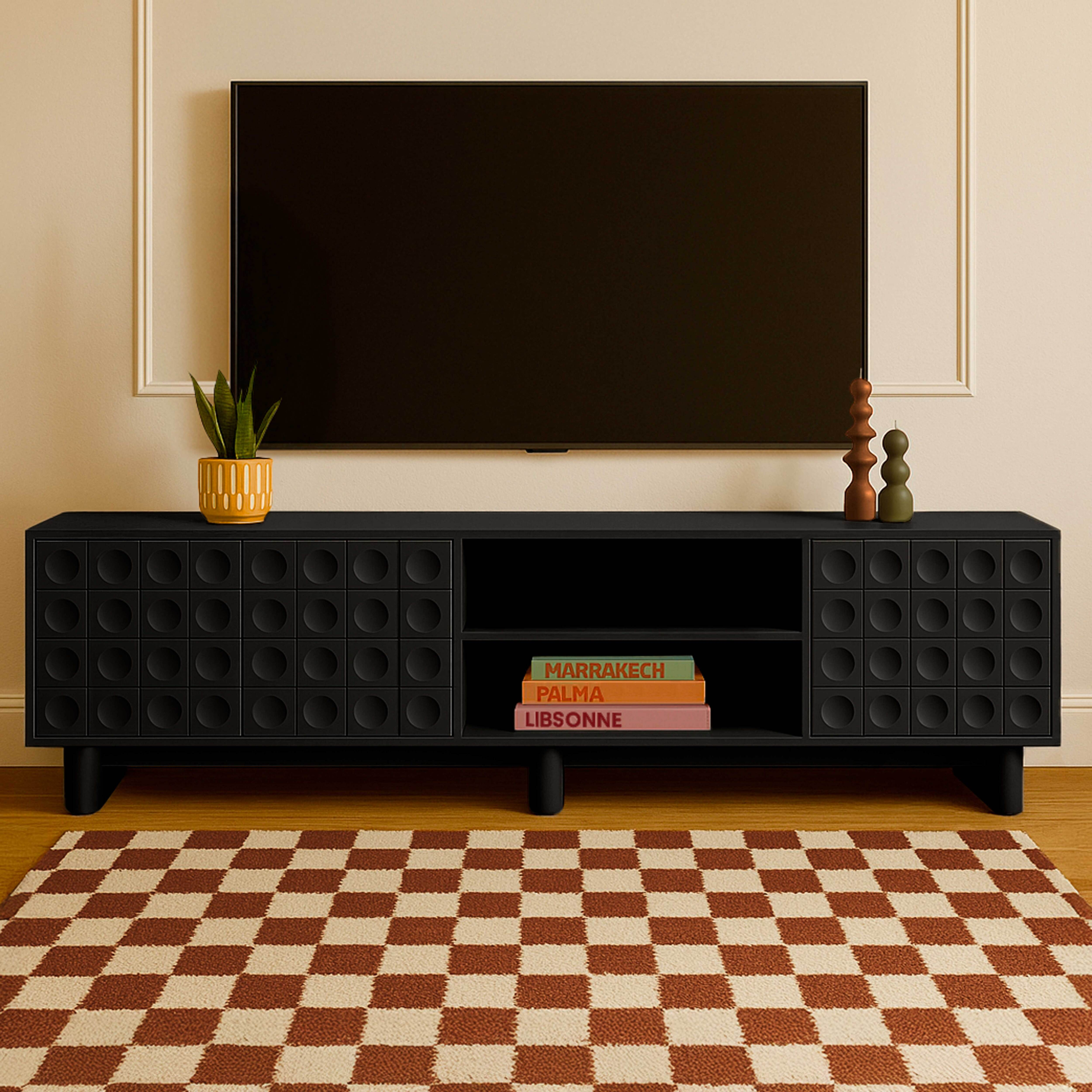 TV-Ständer mit Pflanze, Kerzen und Büchern unter einem an der Wand montierten Fernseher.
