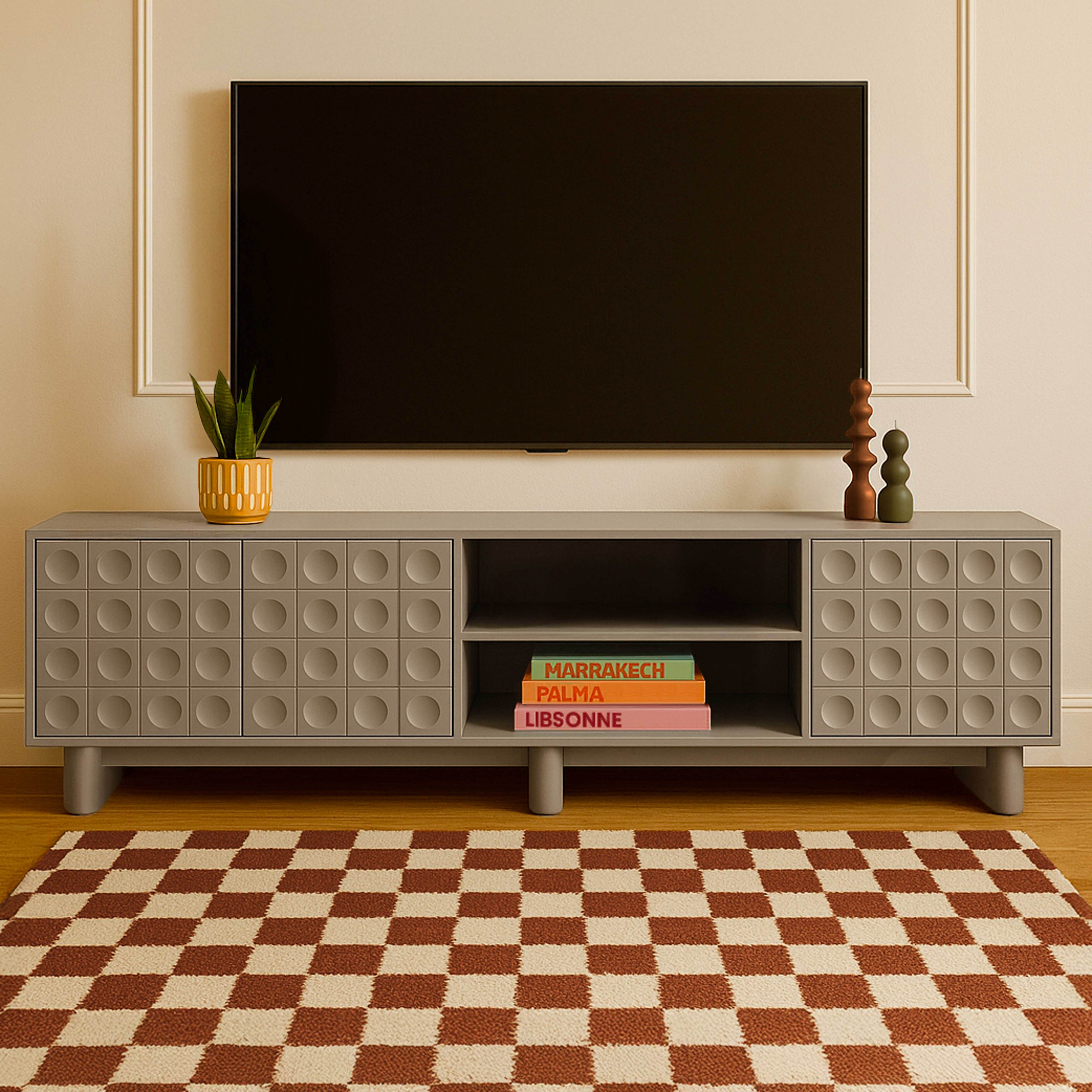 Grauer TV-Ständer mit Pflanze, Kerzen und Büchern unter einem an der Wand montierten Fernseher.