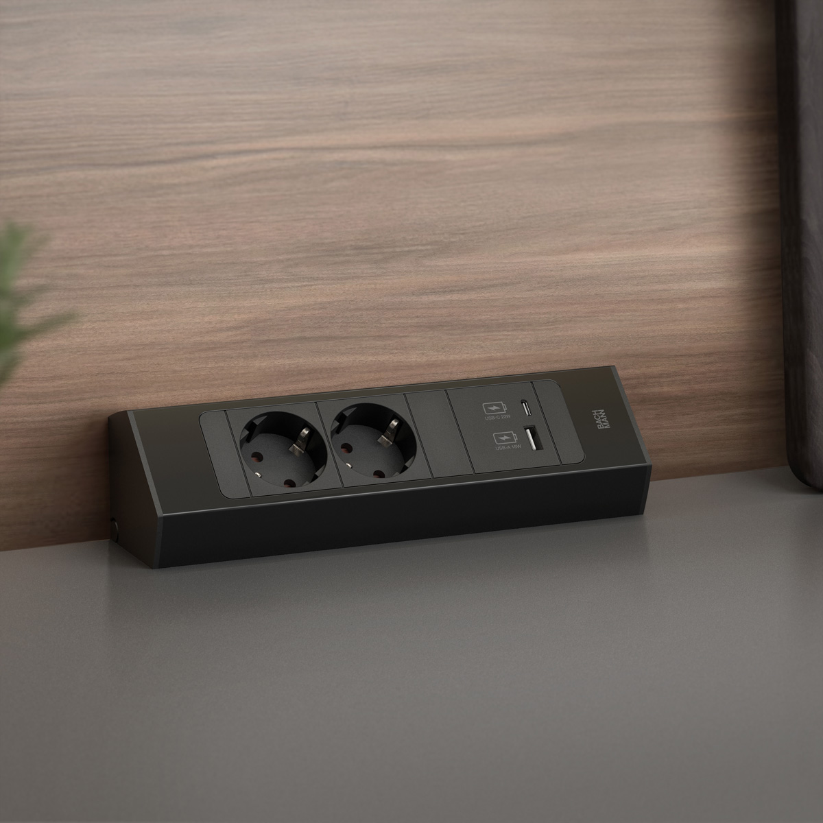 Zwart stopcontact met twee stopcontacten en USB-poorten op een grijs aanrecht.
