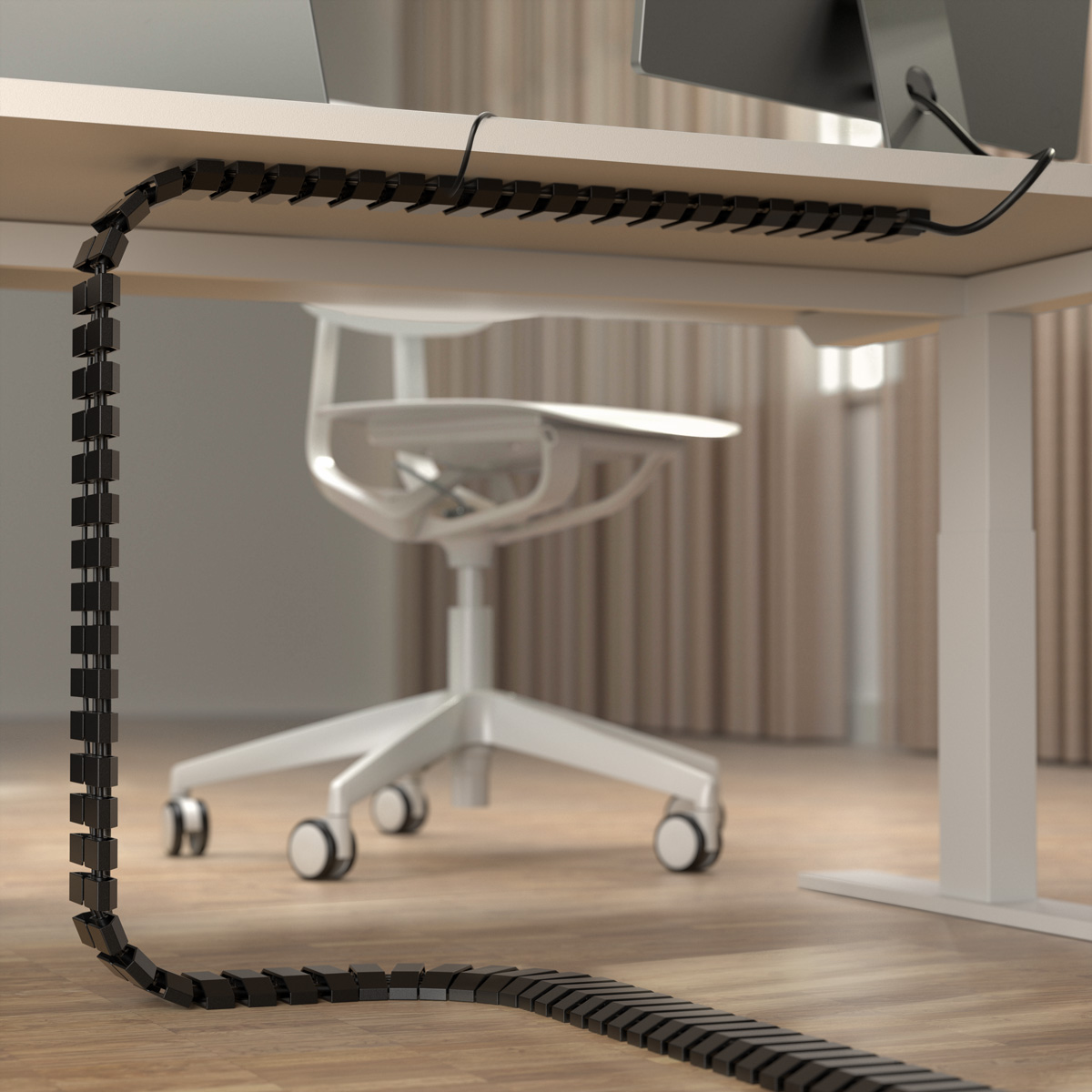 Black cable management system hanging under a white desk with a rolling chair.