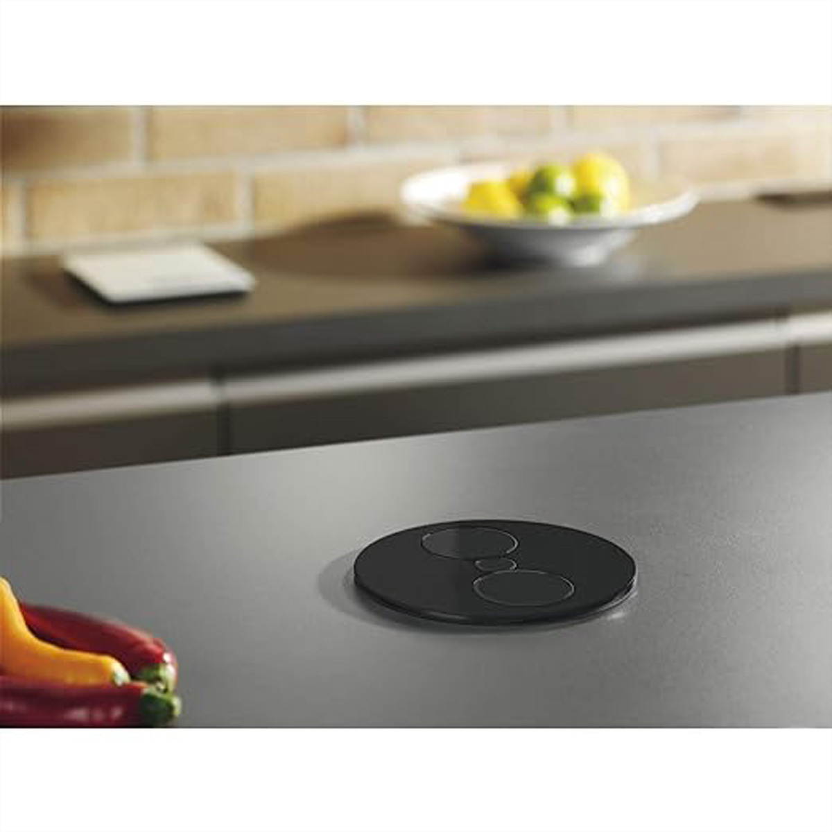 Czarne gniazdo na blacie z miską cytryn i papryką na pierwszym planie.