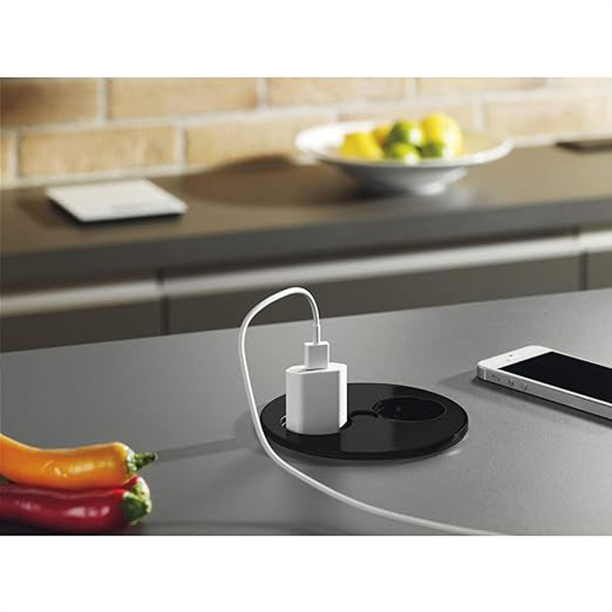 Czarne gniazdo z ładowarką i telefonem na blacie.