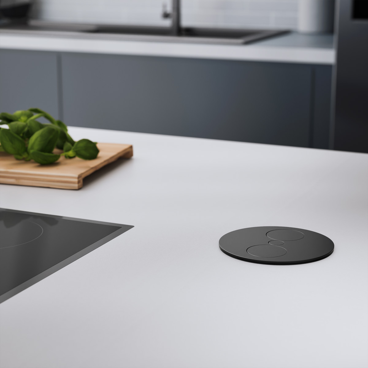 Un piano cucina con una presa di corrente nera e circolare. Un piano cottura e basilico sono visibili sullo sfondo.