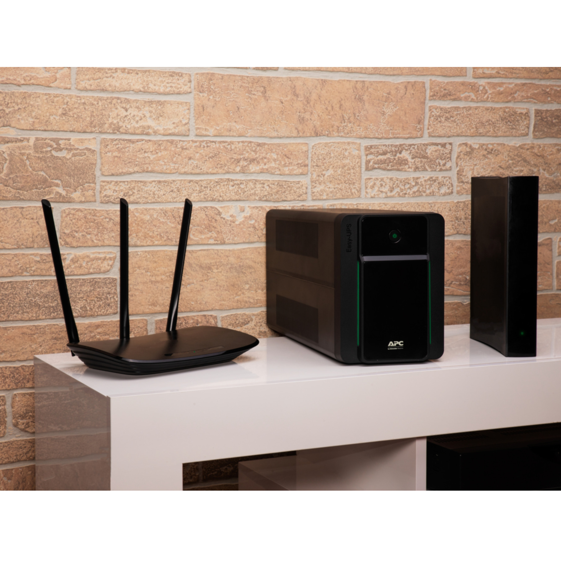 Router con antenne e UPS con scatola nera. Superficie bianca su muro di mattoni.