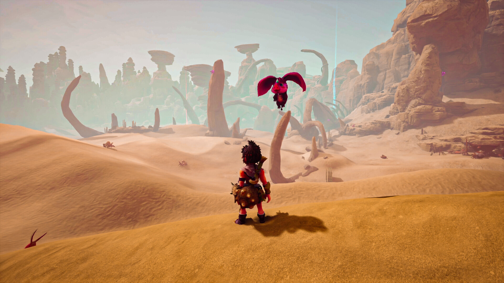 Postać stoi na pustynnym wzgórzu, patrząc na latające stworzenie w tętniącym życiem krajobrazie.