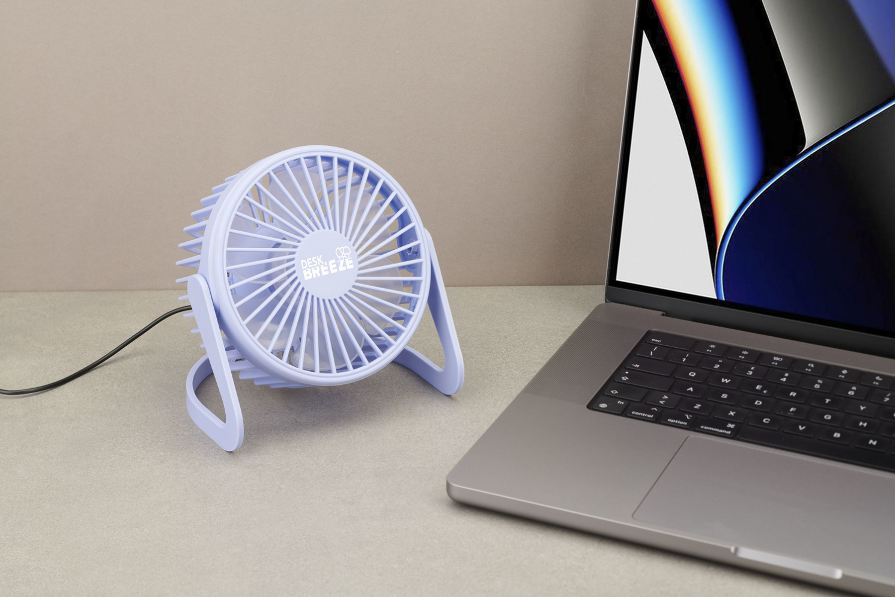 Un ventilador de escritorio pequeño y azul claro está sobre una mesa junto a una laptop.