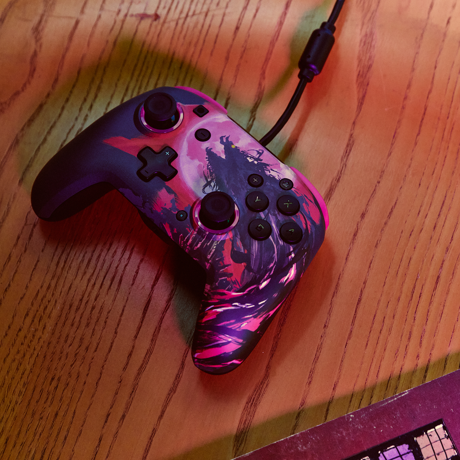 Kontroler z ciemnym wzorem na drewnianym stole. Kontroler jest podłączony do kabla.