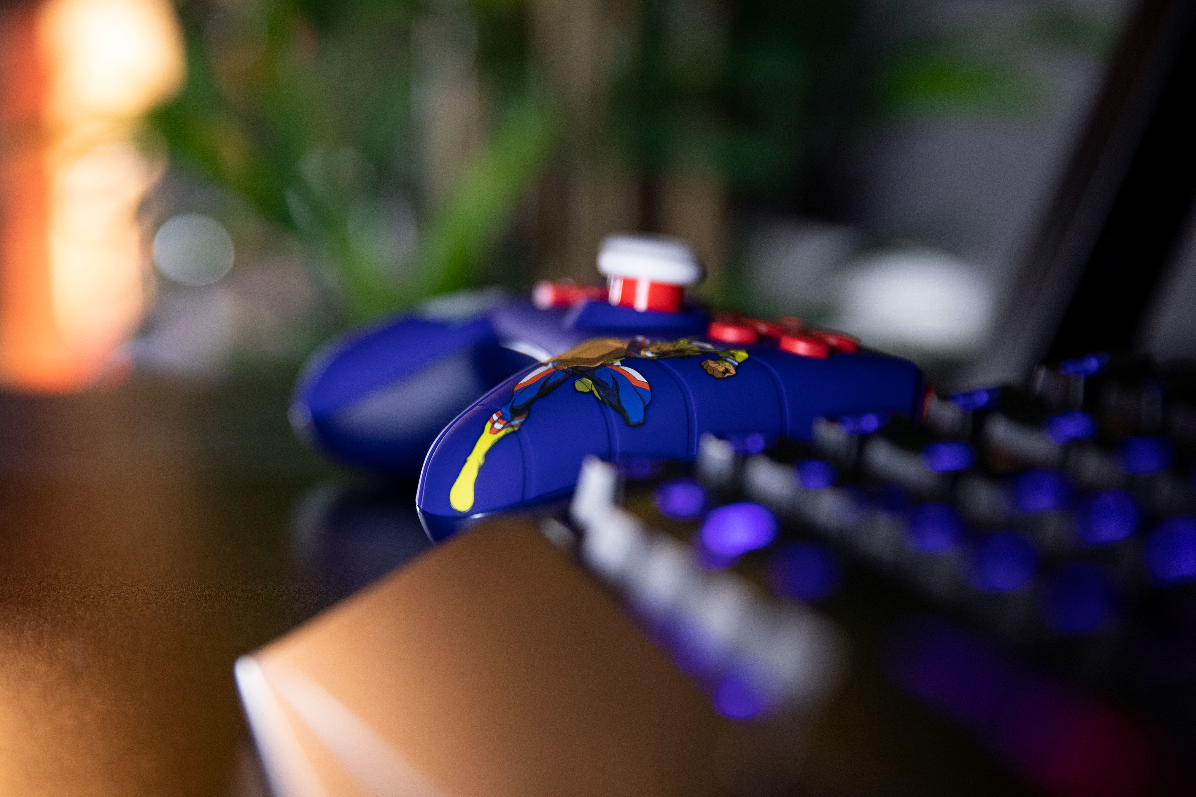 Un controller blu con dettagli gialli e rossi, con una tastiera sullo sfondo.