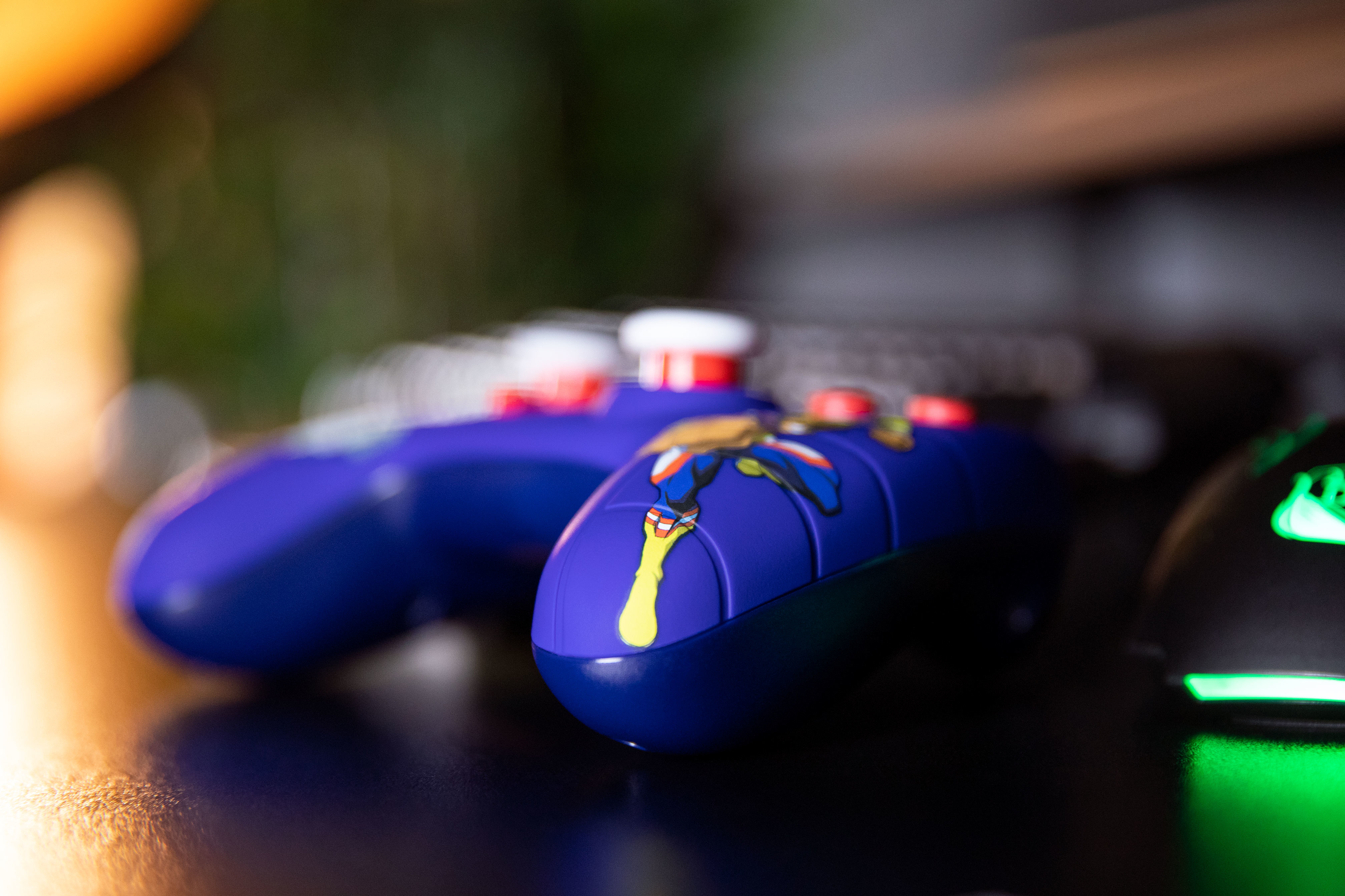 Due controller blu con dettagli gialli e rossi, su una superficie scura, sfondo sfocato.