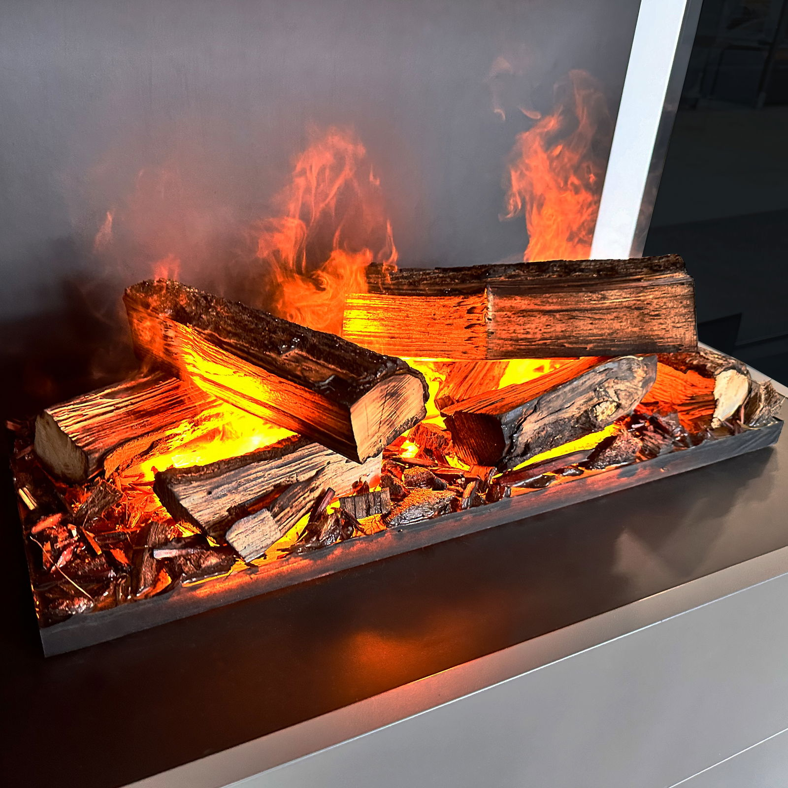 Kamin mit Holzscheiten und Flammen. Die Holzscheite sind entzündet und scheinen zu brennen. Der Hintergrund ist neutral.