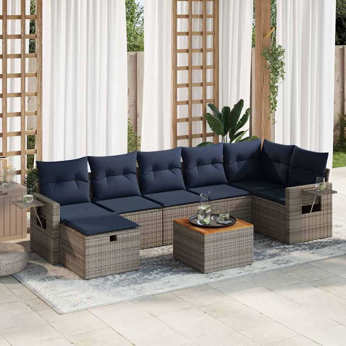 Outdoor-Ecksofa mit grauem Weidengeflecht, blauen Kissen und quadratischem Couchtisch. Weiße Vorhänge im Hintergrund.