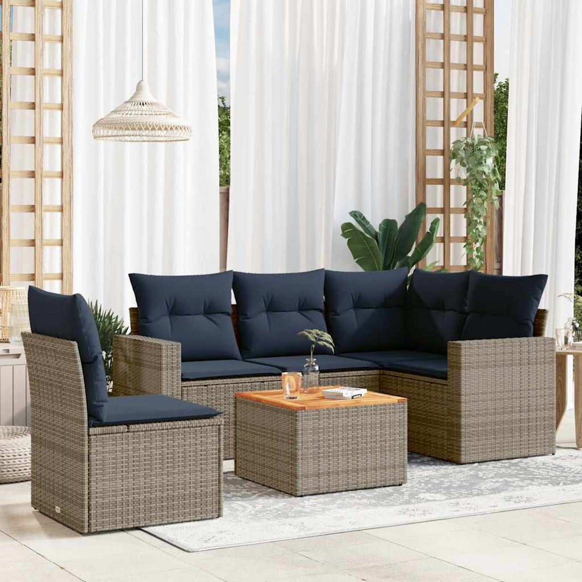 Ein Terrassenset mit grauem Korbgeflecht und dunkelblauen Kissen. Enthält Sofa, Stuhl, Tisch, mit Deko.