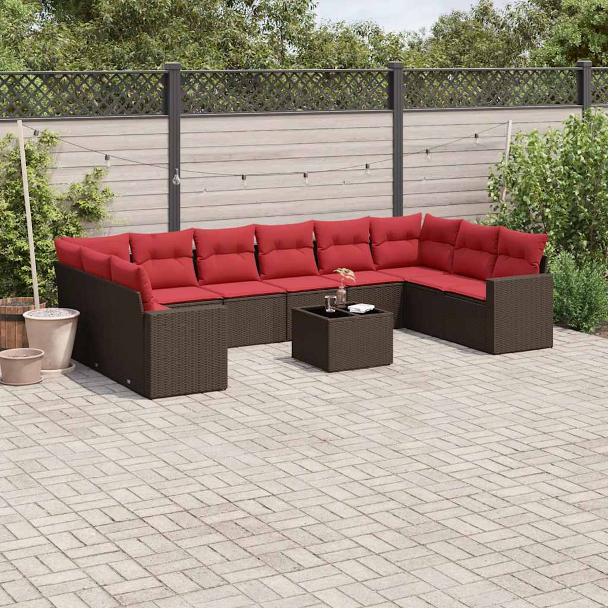 Ein Outdoor-Schnitt mit roten Kissen und einem Couchtisch auf einer Terrasse. Der Hintergrund ist ein Garten.