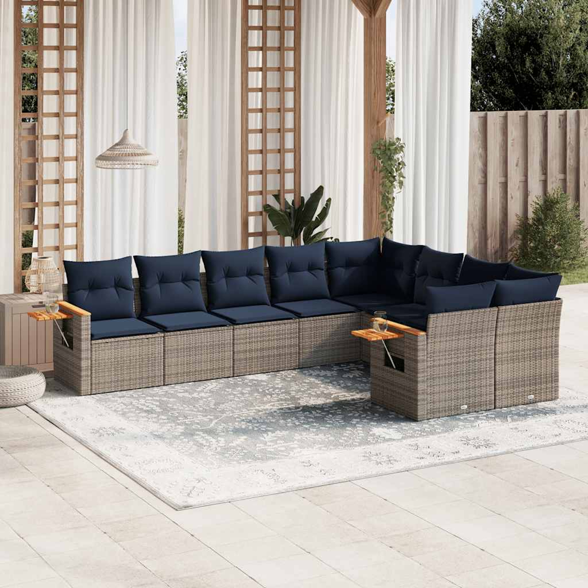 Graues Ecksofa aus Korbgeflecht mit marineblauen Kissen. Weiße Vorhänge, Teppich, Holztische.