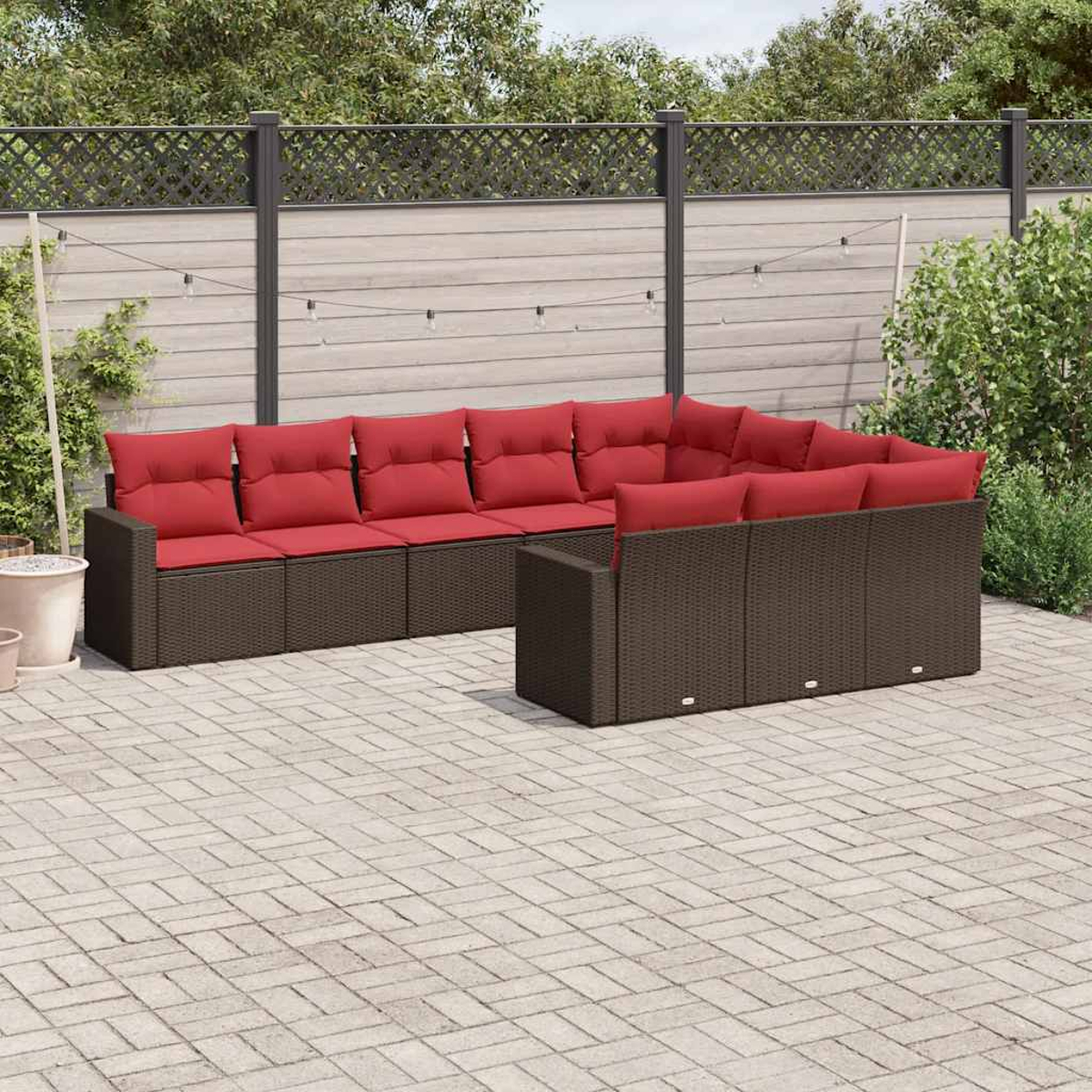 Braunes Korbmöbel-Sofa mit roten Kissen im Freien auf einer Ziegelterrasse.