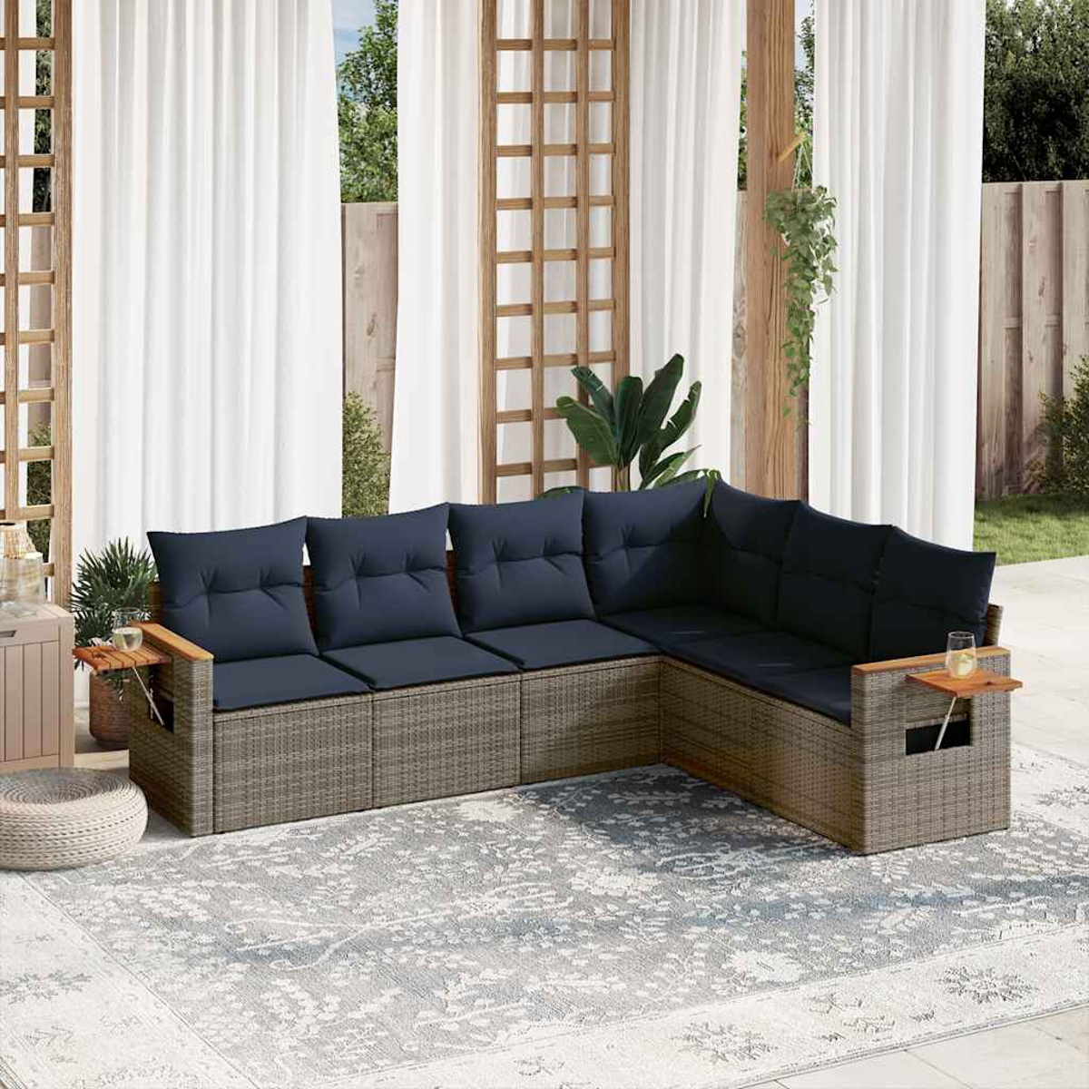 Gartenmöbel-Set mit Ecksofa und Couchtisch. Graues Korbgeflecht, blaue Kissen und ein Teppich. Vorhänge.