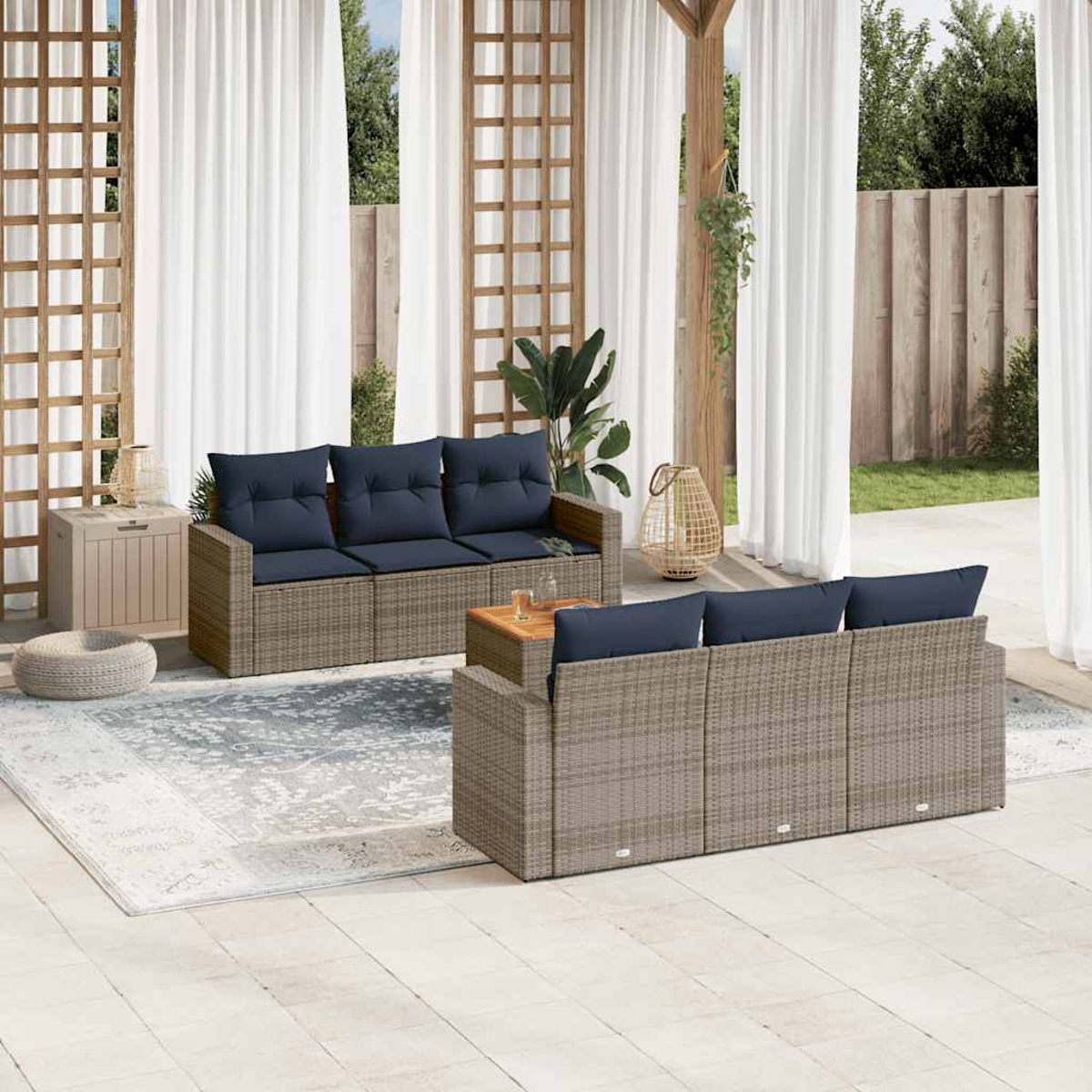 Outdoor-Terrassenset mit grauen Rattansofas, blauen Kissen, kleinem Tisch, Teppich und Vorhängen.