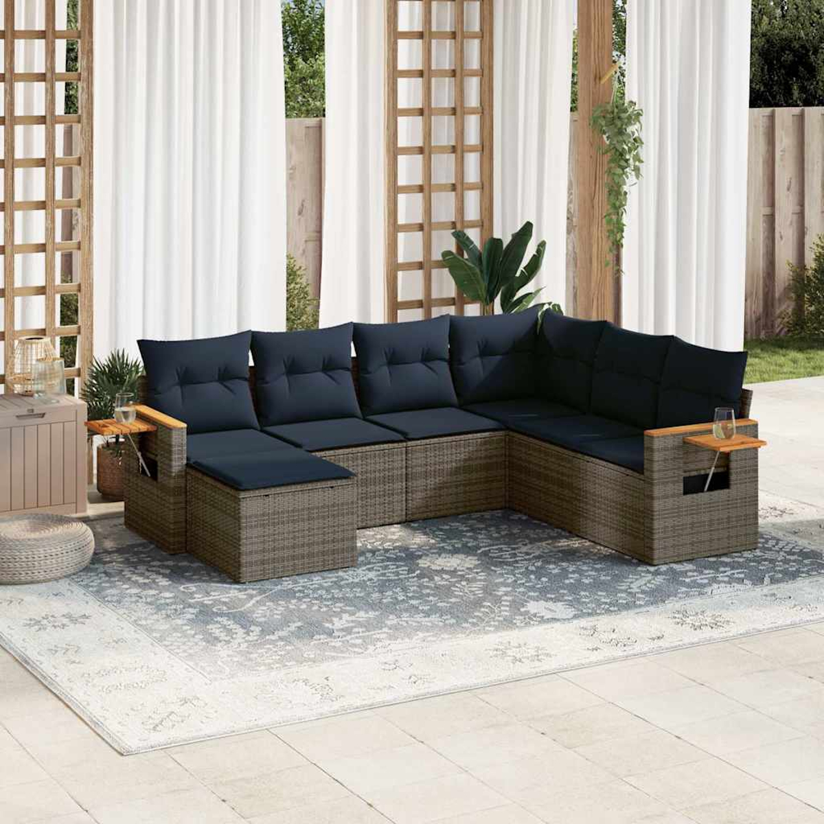 Outdoor-Terrassenset mit grauem Rattansofa, blauen Kissen, kleinen Beistelltischen und einem Teppich.