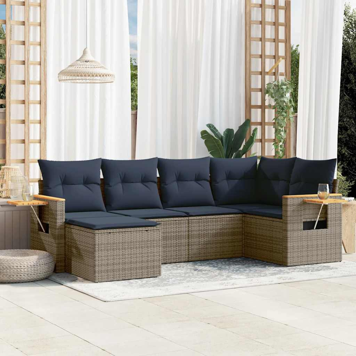 Outdoor-Terrassenset mit grauem Rattansofa, blauen Kissen, kleinen Beistelltischen und einem Teppich.