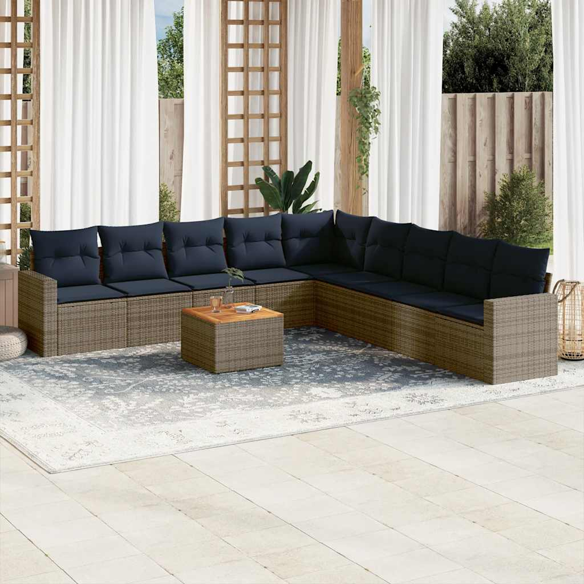 Ein braunes Ecksofa aus Korbgeflecht mit marineblauen Kissen und einem kleinen Tisch auf einer Terrasse mit Vorhängen.