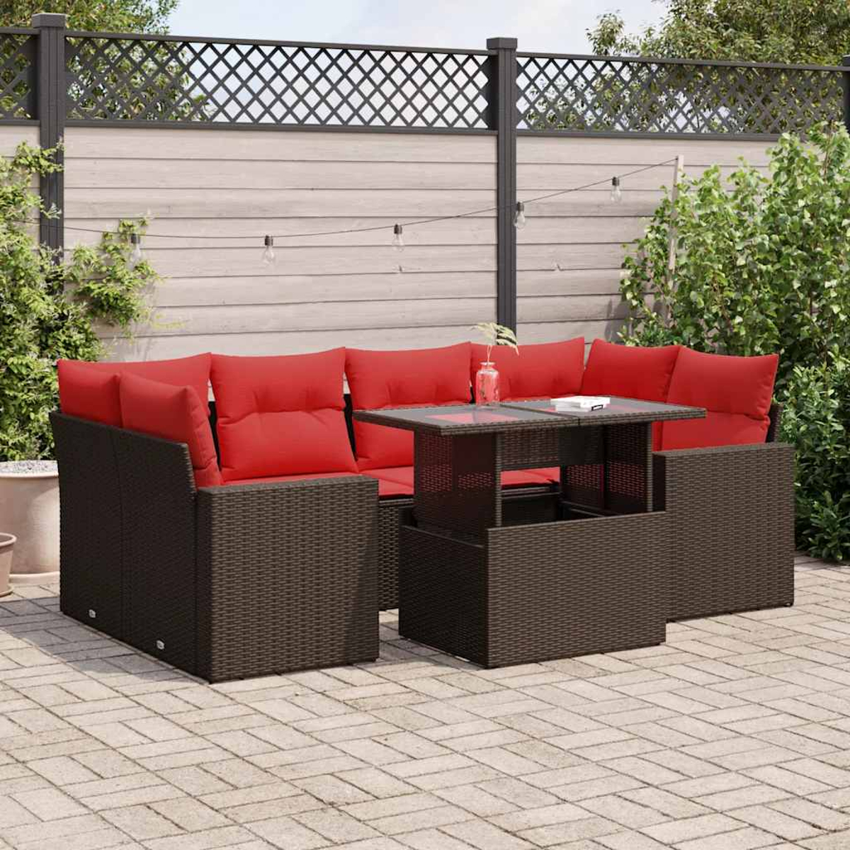 Ein dunkelbraunes Outdoor-Sofa-Set aus Korbgeflecht mit roten Kissen und einem Tisch auf einer Ziegelterrasse.