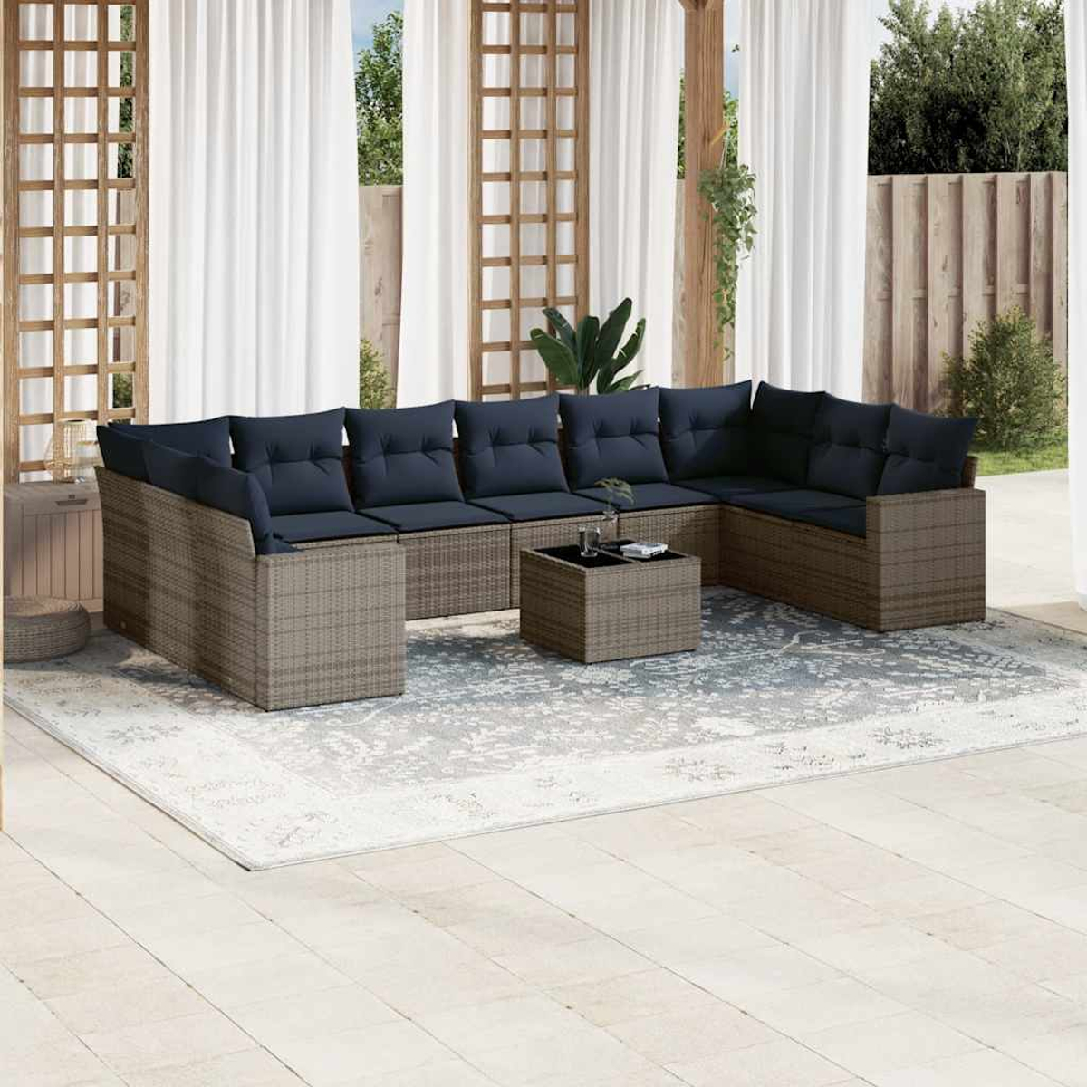 Outdoor-Rattan-Möbelset mit dunkelblauen Kissen, auf einem weißen Teppich und einem Garten.