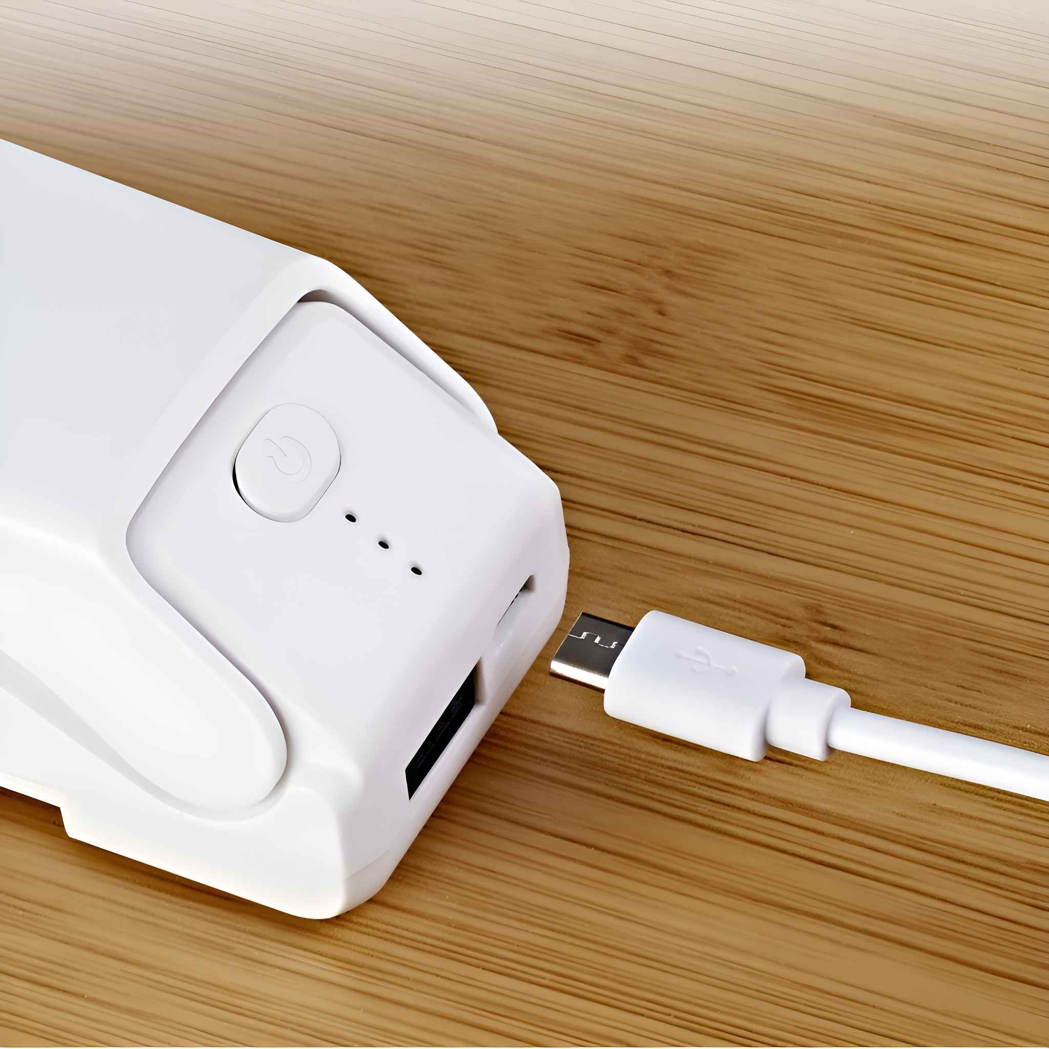 Eine weiße Powerbank aus Kunststoff wird mit einem weißen Kabel auf einem Holztisch aufgeladen.