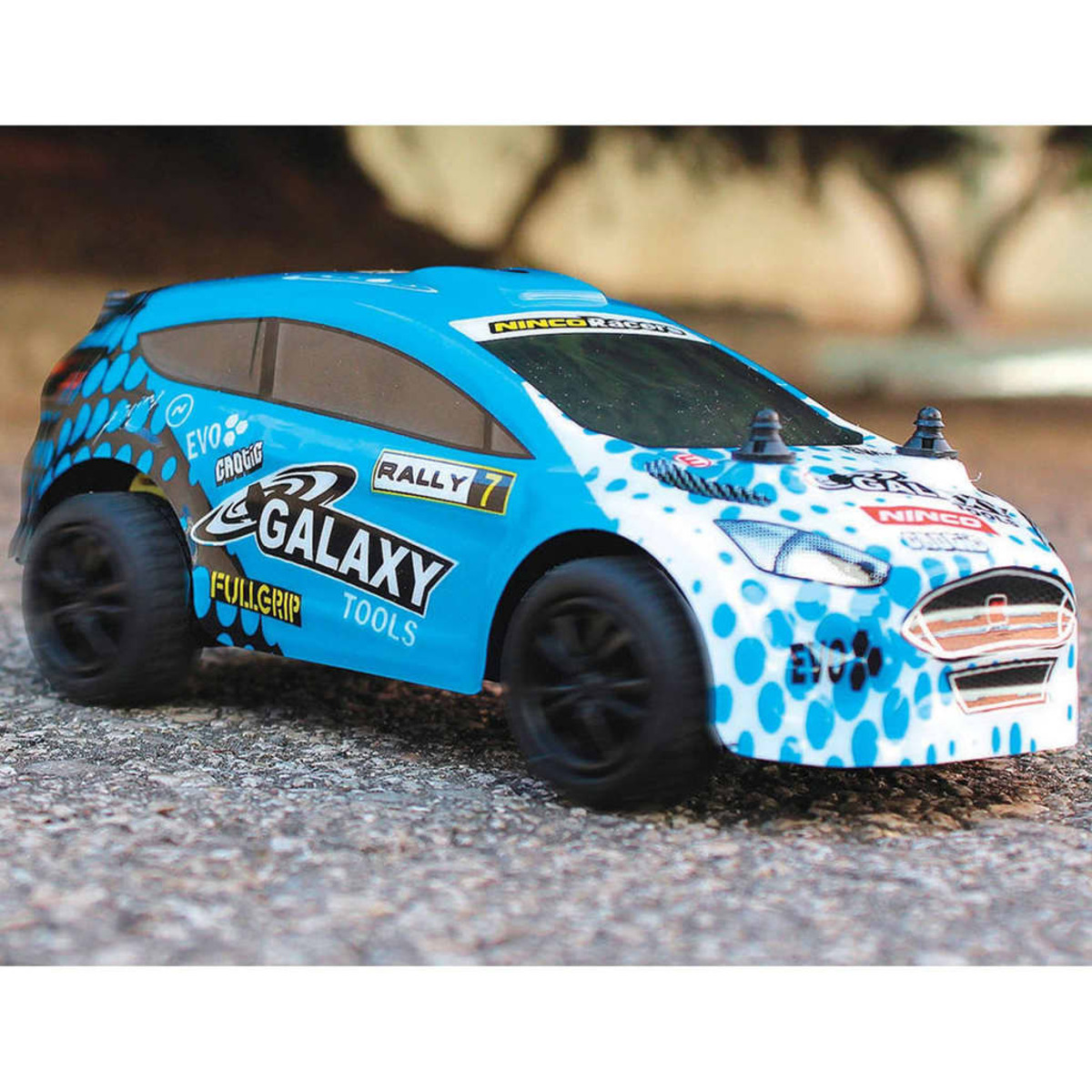 Un coche de juguete azul y blanco con ruedas negras. El coche tiene logotipos y palabras en el lateral.