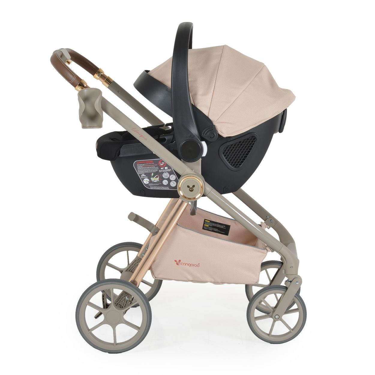 Ein beiger Kinderwagen mit aufgesetztem Autositz, von der Seite betrachtet. Auf weißem Hintergrund.