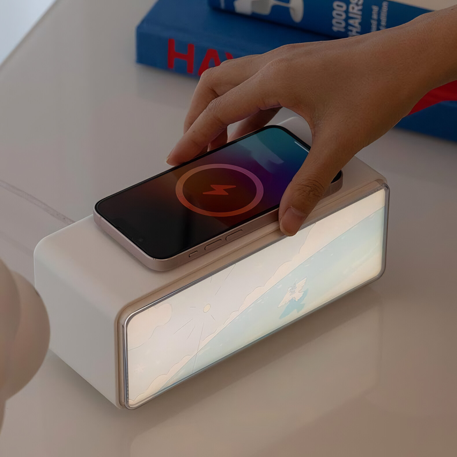 Eine Hand legt ein Telefon auf eine weiße Ladestation mit beleuchtetem Bildschirm.