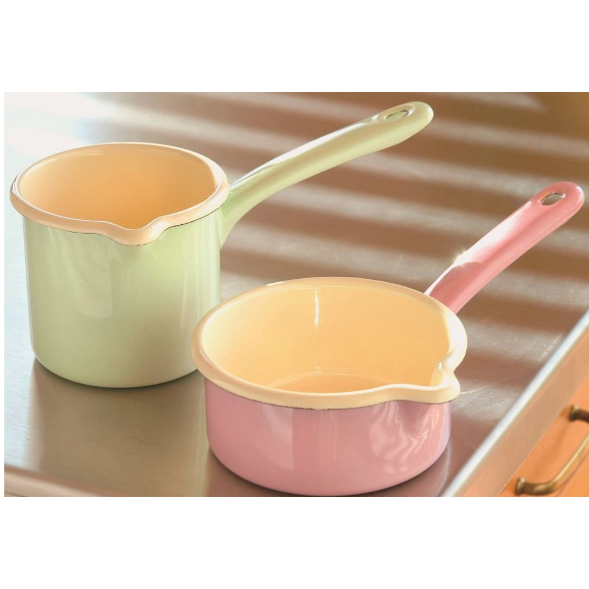 Deux casseroles en émail, une verte et une rose, avec des intérieurs de couleur claire.