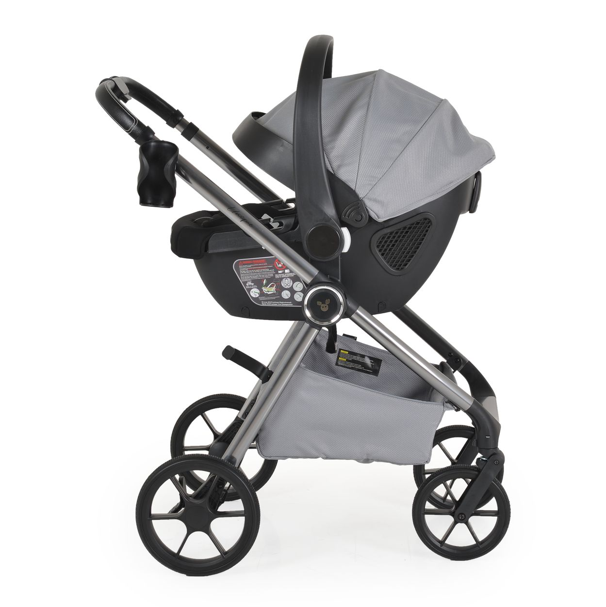 Ein grauer Kinderwagen mit einem Autositz befestigt. Er hat vier Räder und einen Griff. Der Hintergrund ist weiß.